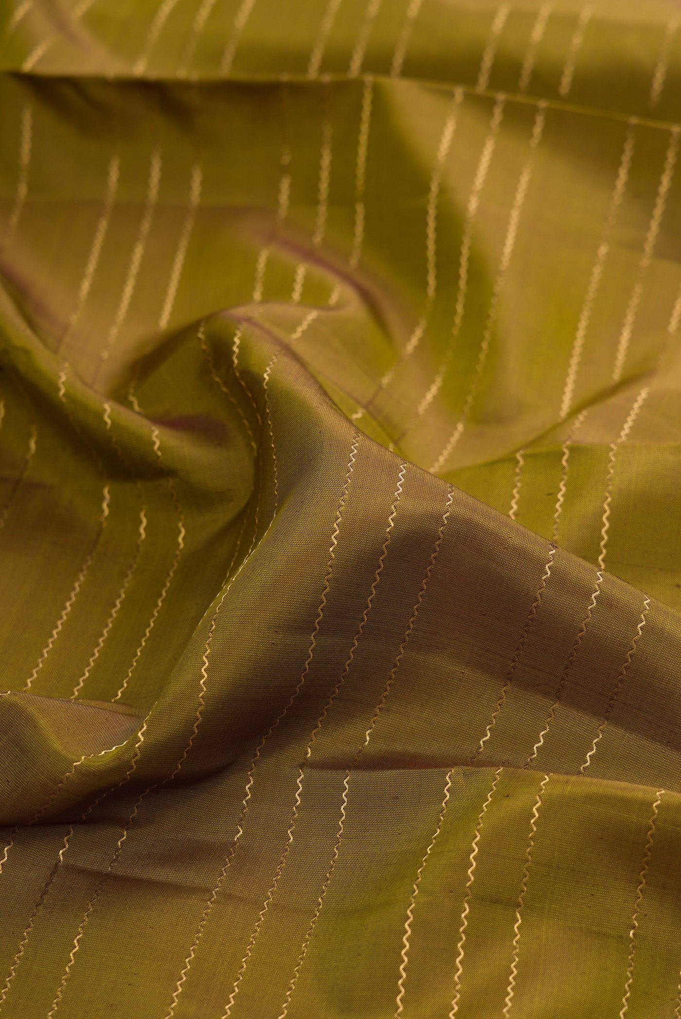 Close up of Mehandi Green Kanchipuram Silk Saree with Veldhari on the body and Zari Border.  displaying folds