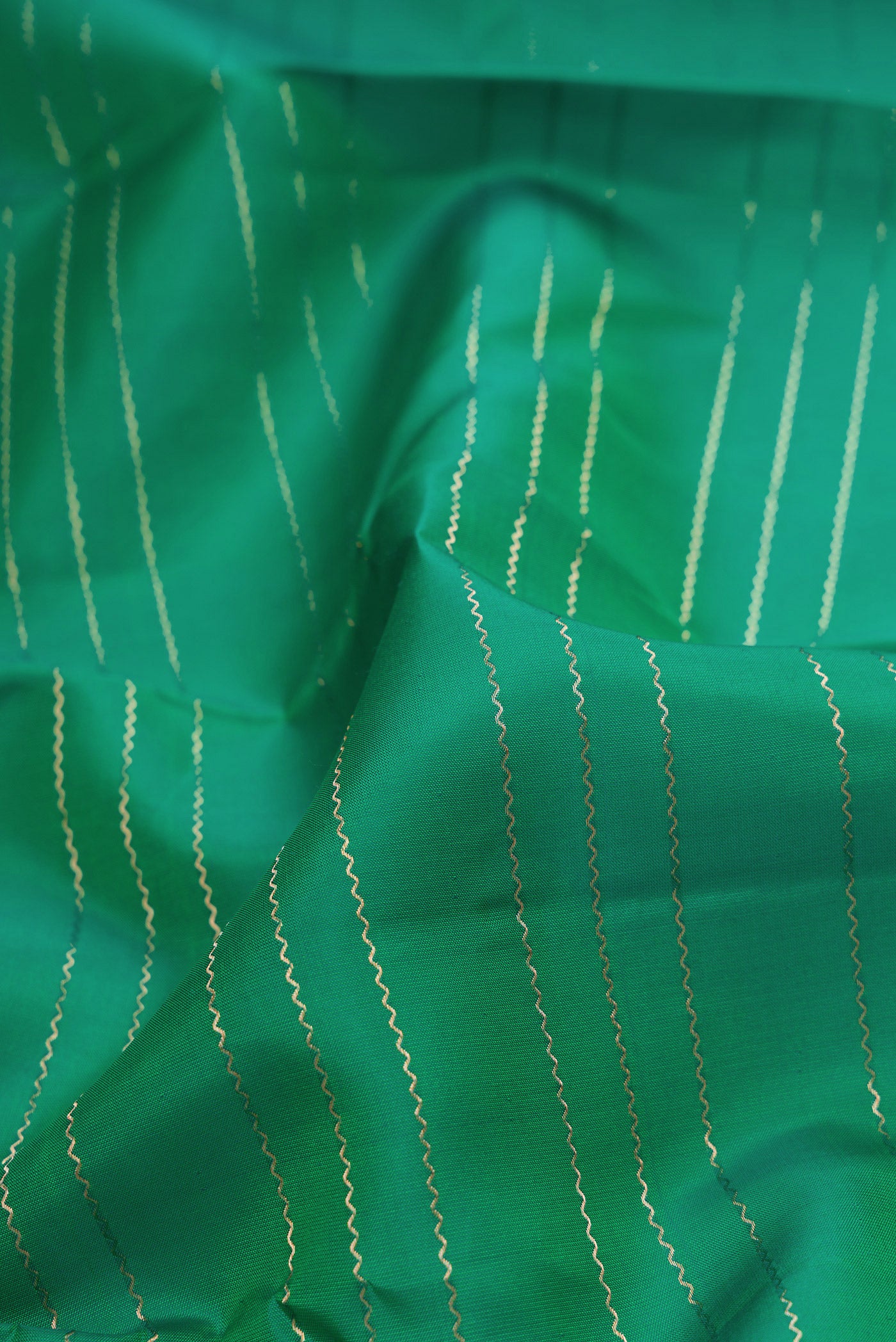 Close up of Bottle Green Dual Tone Kanchipuram Silk Saree with Veldhari on the body and Zari Border.  displaying folds