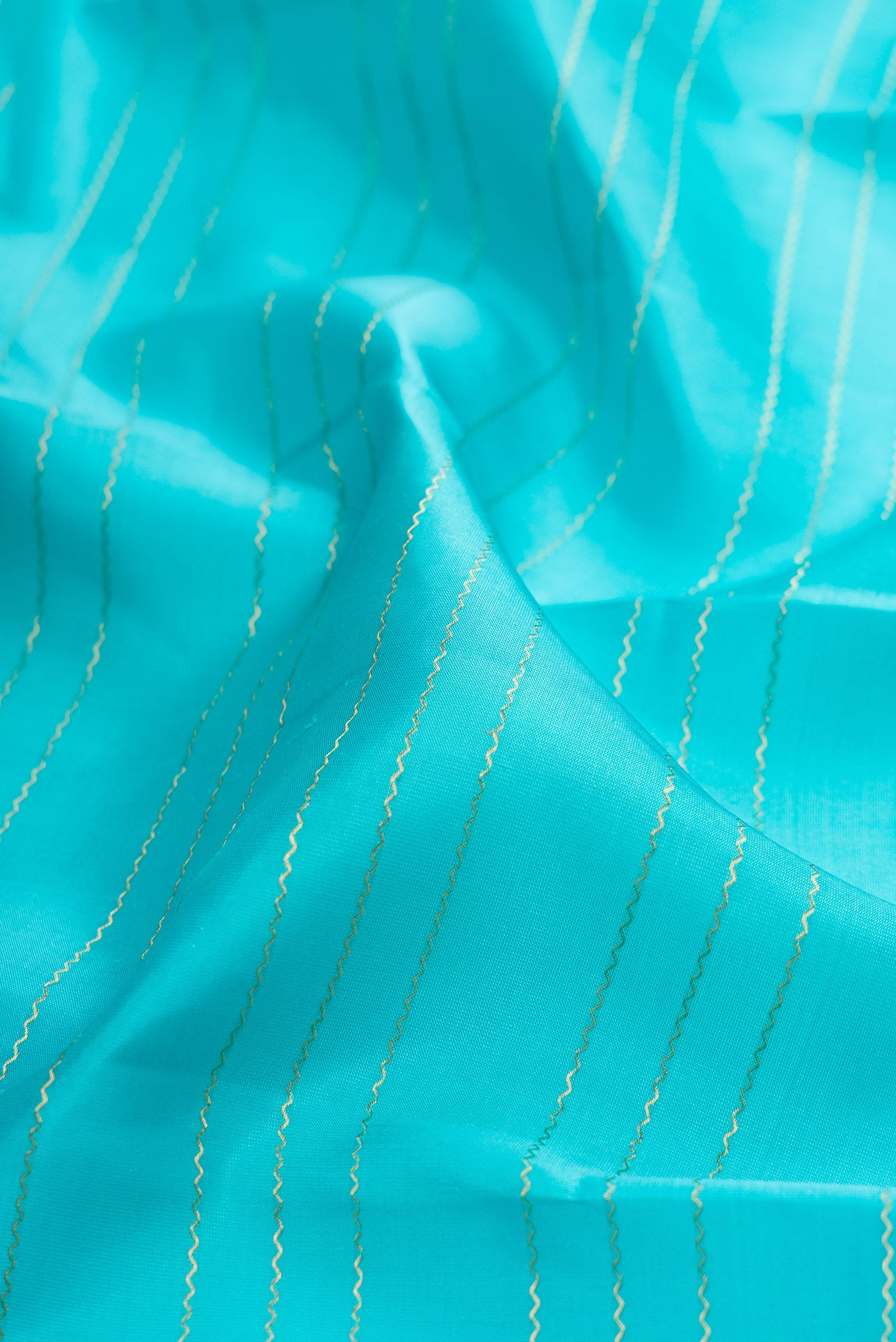 Close up of Sky Blue Kanchipuram Silk Saree with Veldhari on the body and Zari Border.  displaying folds