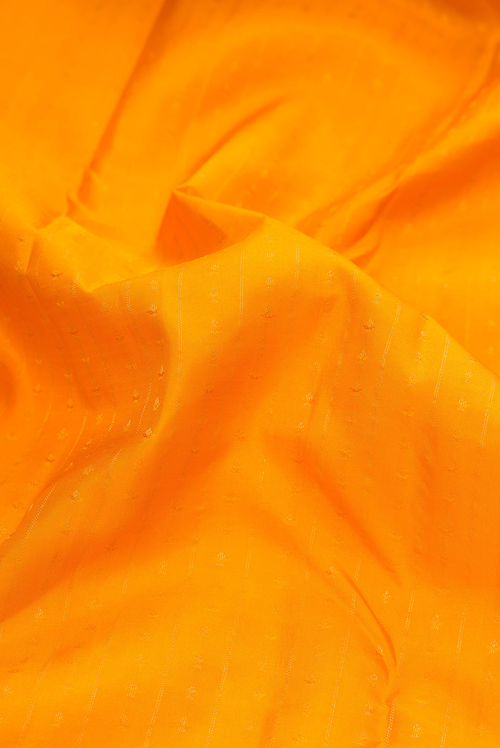 Close up of Mustard Kanchipuram Silk Saree with Zari Butta on the body and Zari Border.  displaying folds