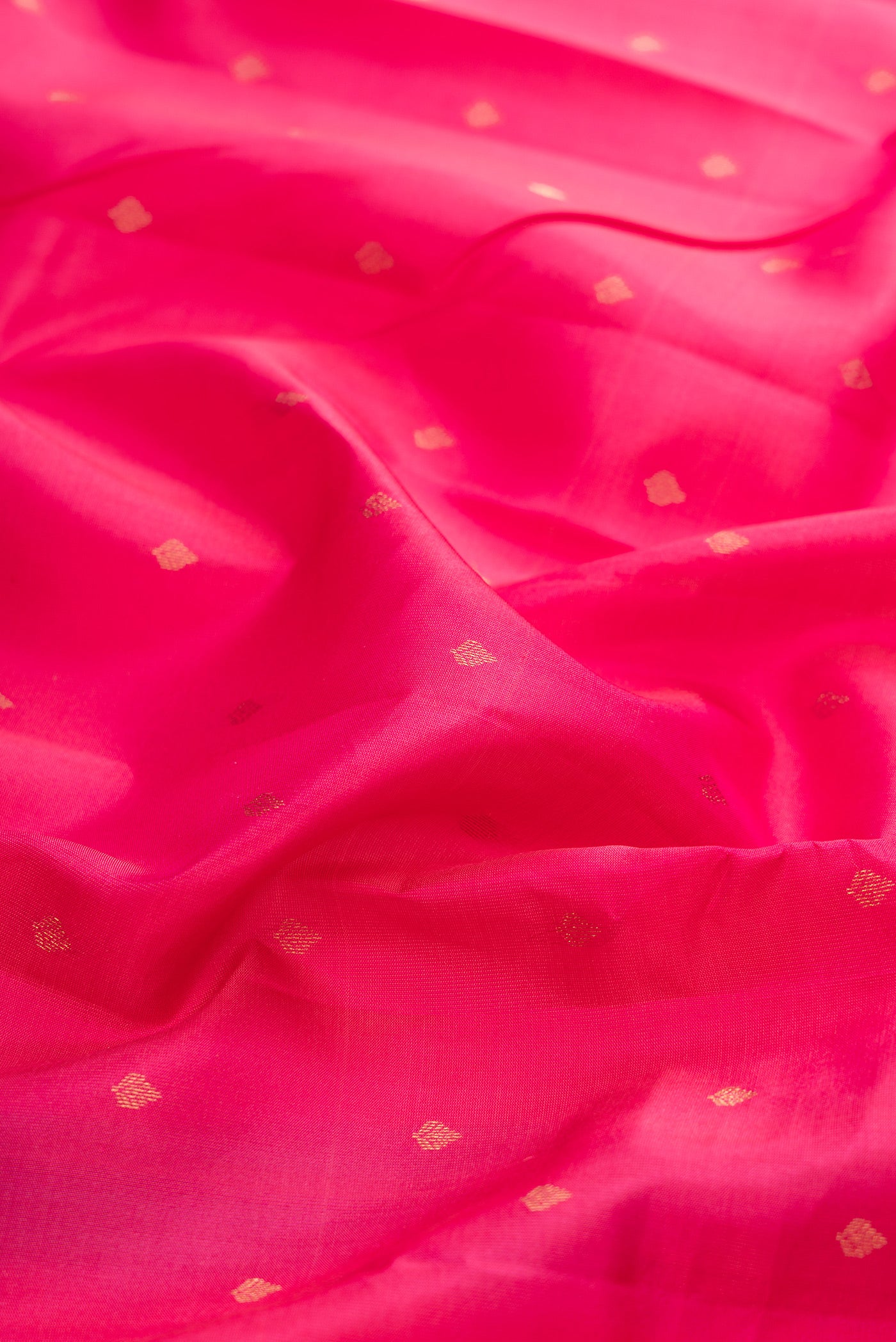 Close up of Dark Pink Kanchipuram Silk Saree with Zari Butta on the body and Zari Border.  displaying folds