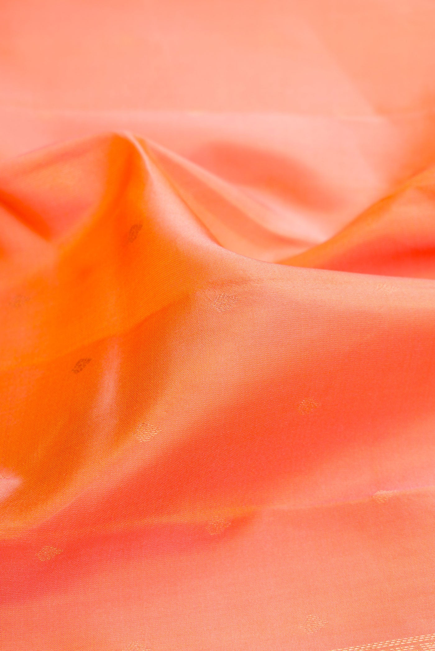 Close up of Golden Peach Kanchipuram Silk Saree with Zari Butta on the body and Fancy Border.  displaying folds