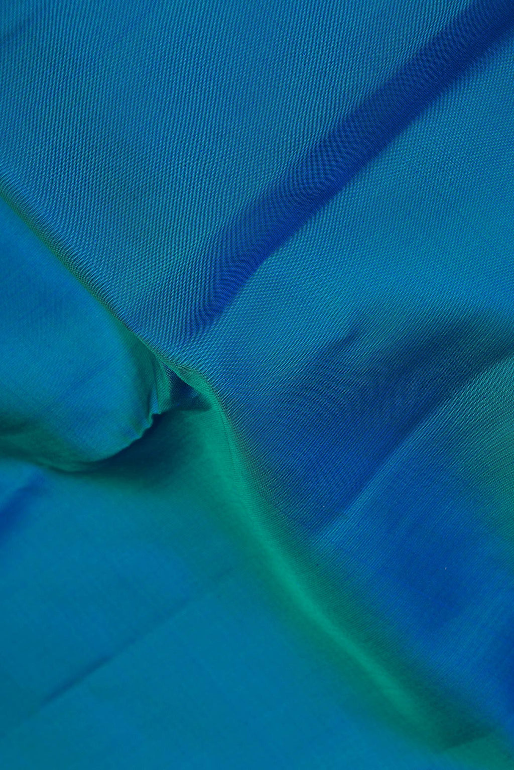 Close up of Pure Silk Peacock Blue Kanchipuram Saree with Plain Body and Zari Border.  displaying folds