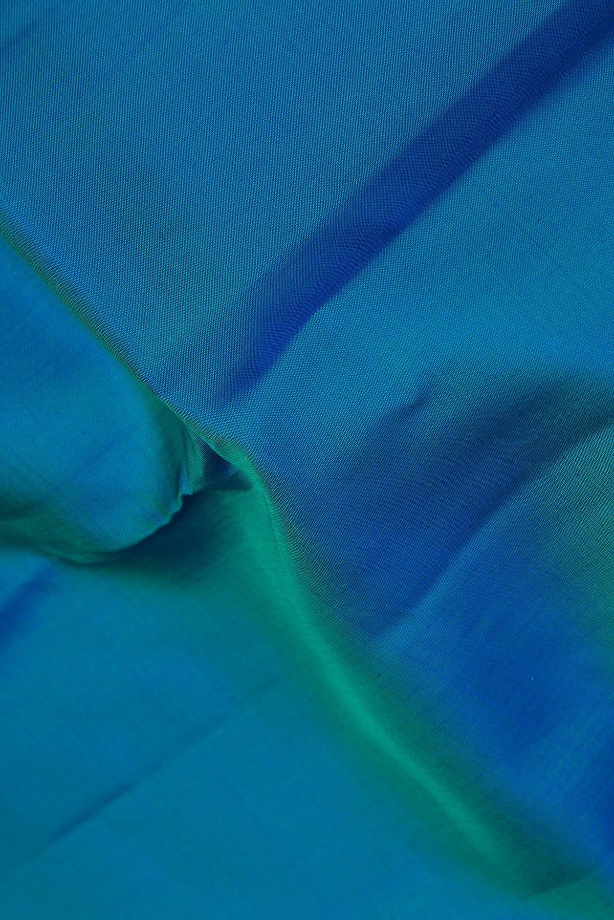 Close up of Pure Silk Peacock Blue Kanchipuram Saree with Plain Body and Zari Border.  displaying folds
