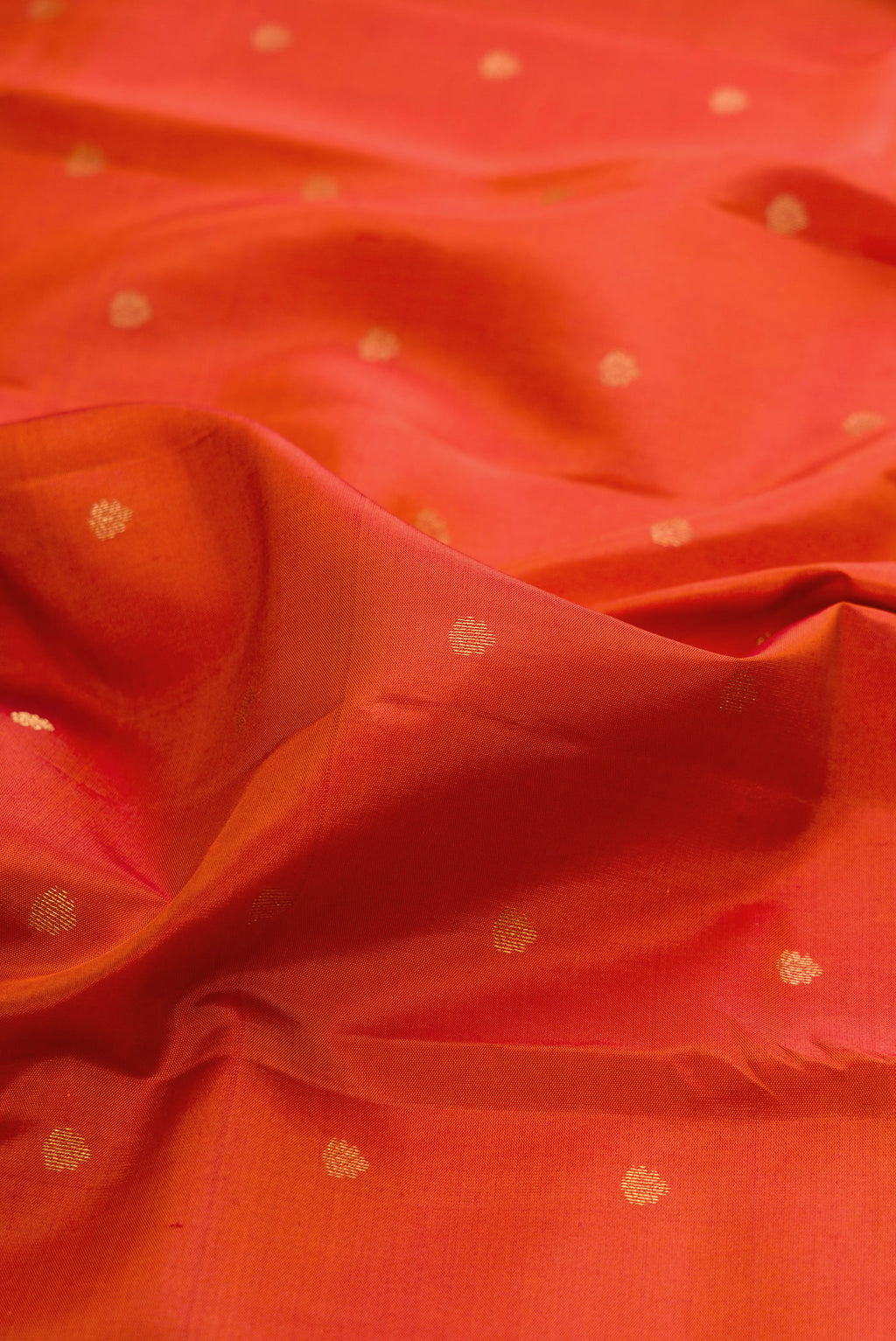 Close up of Brick Orange Kanchipuram Silk Saree with Zari Butta on the body and Zari Border.  displaying folds