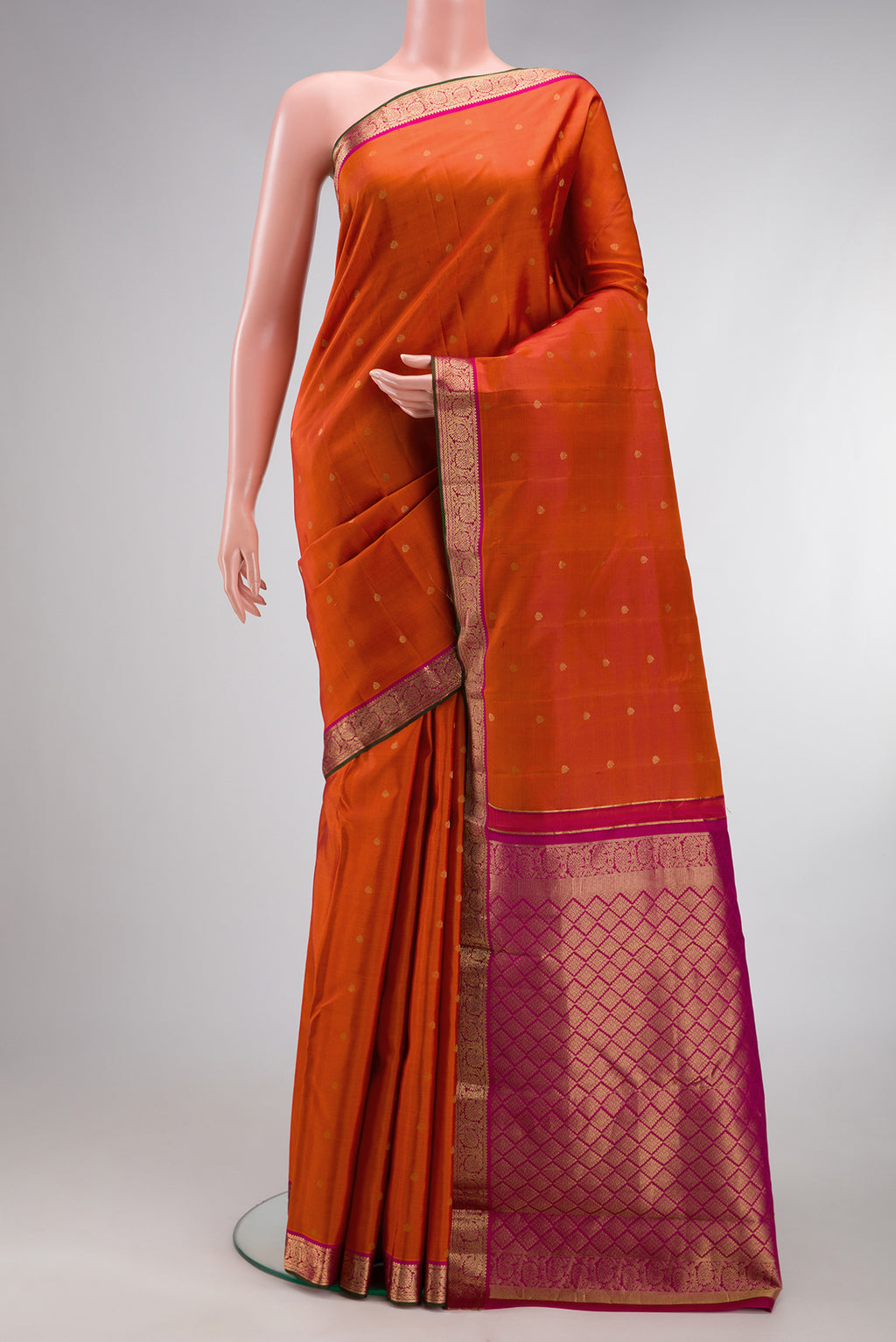 Brick Orange Kanchipuram Silk Saree with Zari Butta on the body and Zari Border.  displayed on a mannequin