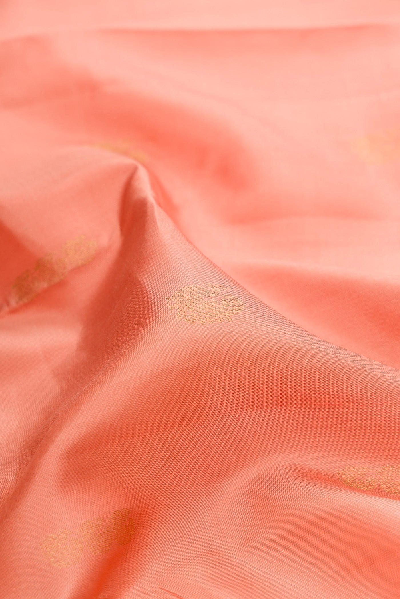 Close up of Pure Silk Golden Peach Kanchipuram Saree with Zari Butta on the body and Zari Border.  displaying folds