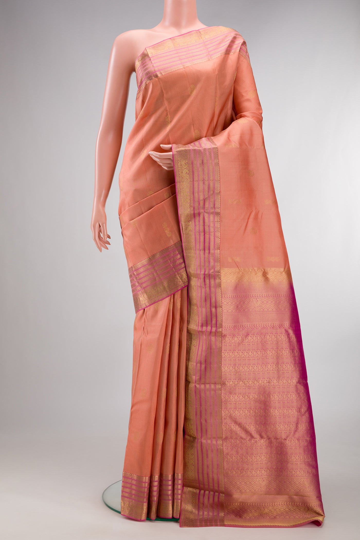 Pure Silk Golden Peach Kanchipuram Saree with Zari Butta on the body and Zari Border.  displayed on a mannequin