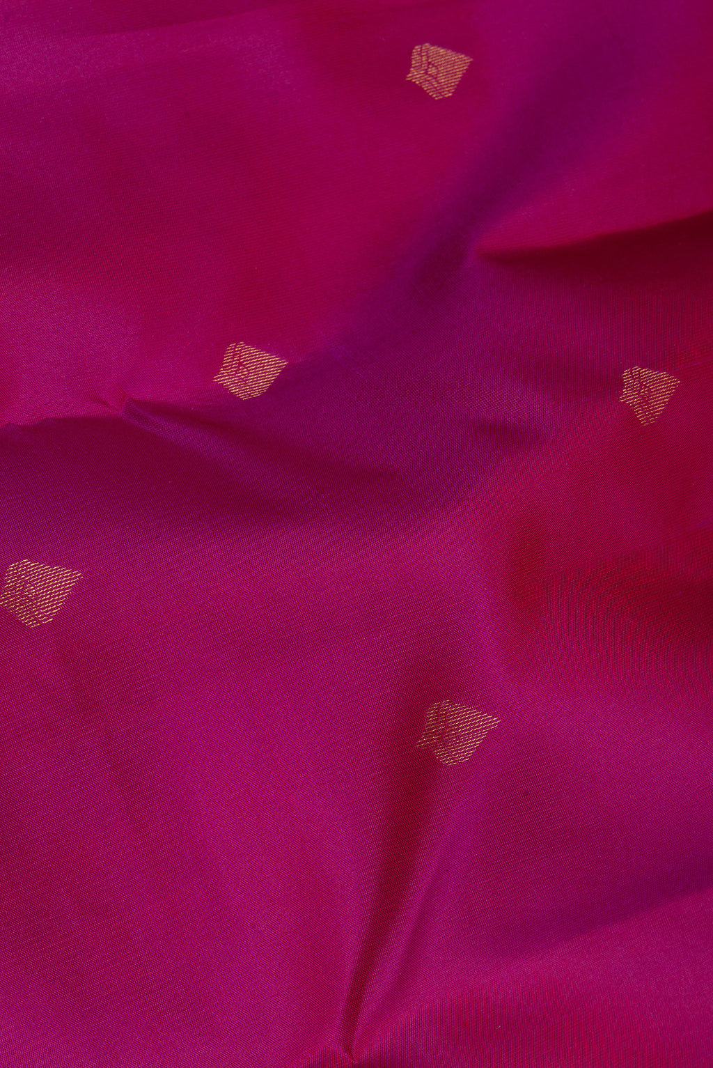 Close up of Magenta Kanchipuram Silk Saree with Zari Butta on the body and Zari Border.  displaying folds
