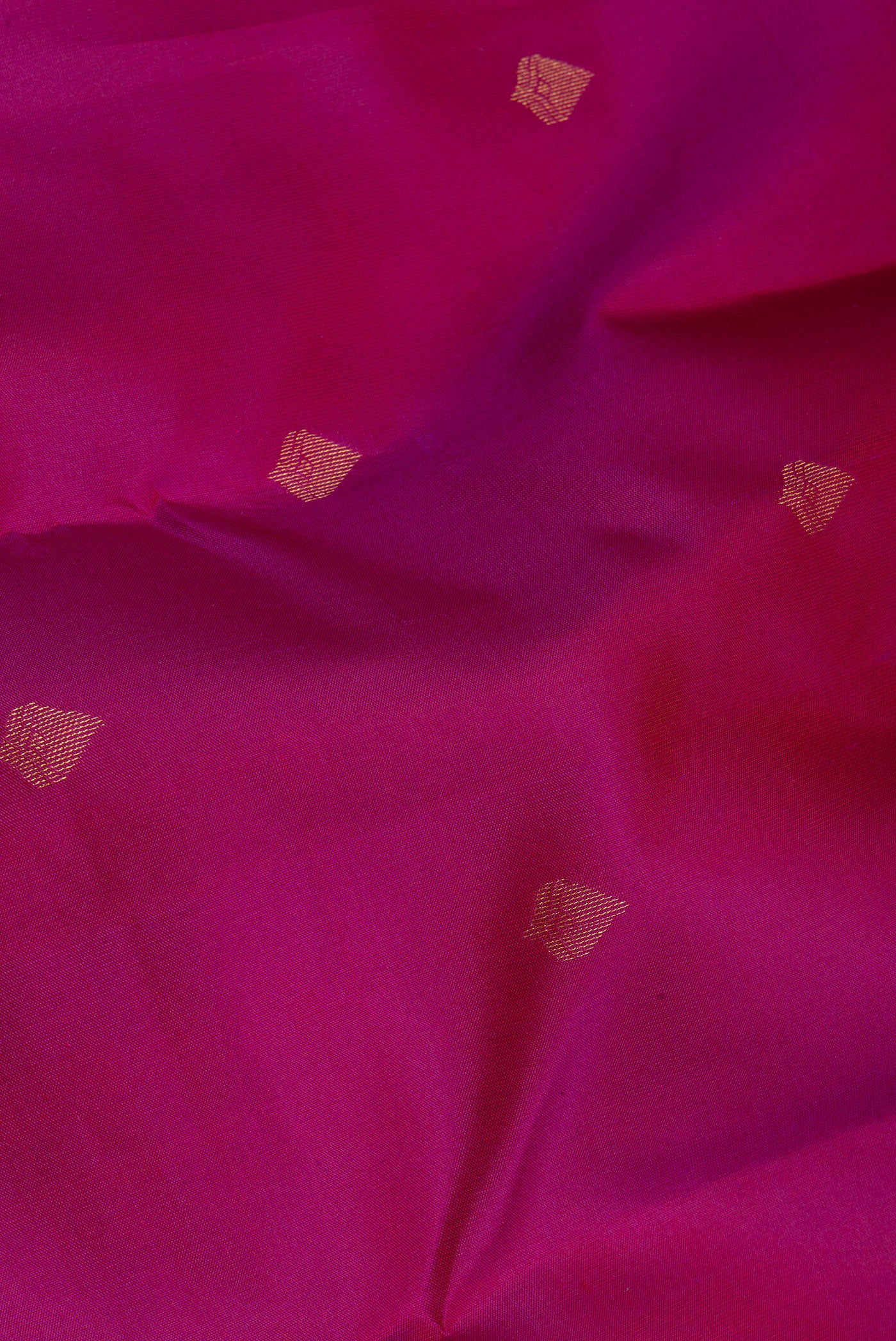 Close up of Magenta Kanchipuram Silk Saree with Zari Butta on the body and Zari Border.  displaying folds