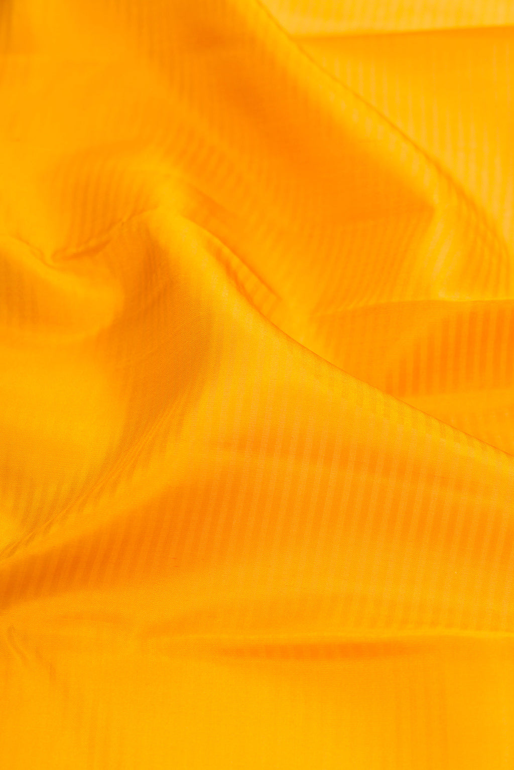 Close up of Mustard Kanchipuram Silk Saree with Stripes on the body and Zari Border.  displaying folds