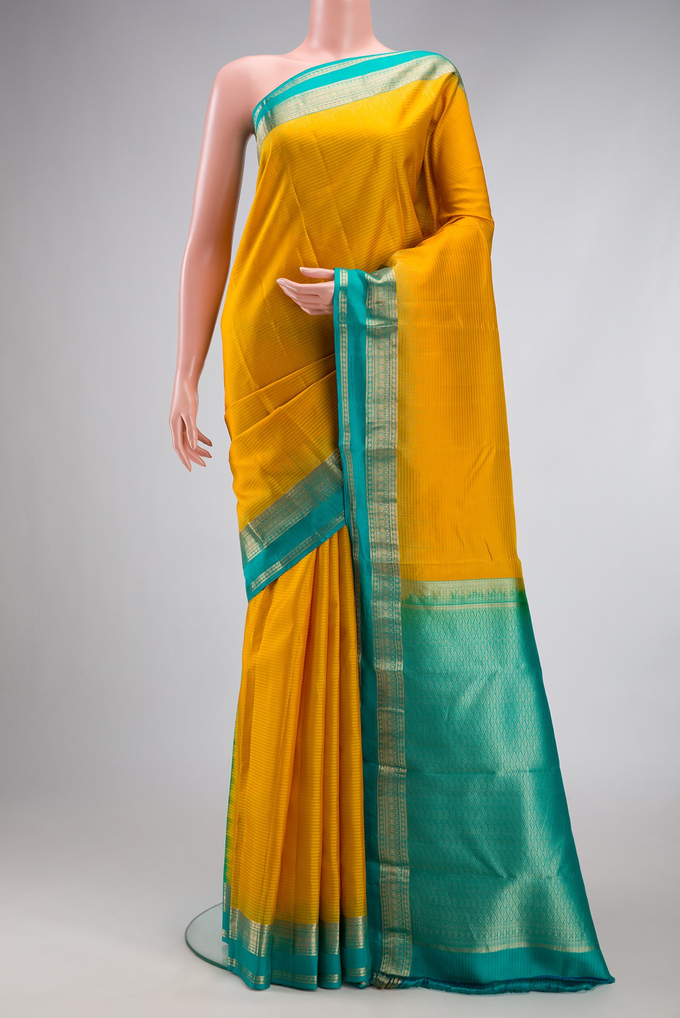 Mustard Kanchipuram Silk Saree with Stripes on the body and Zari Border.  displayed on a mannequin