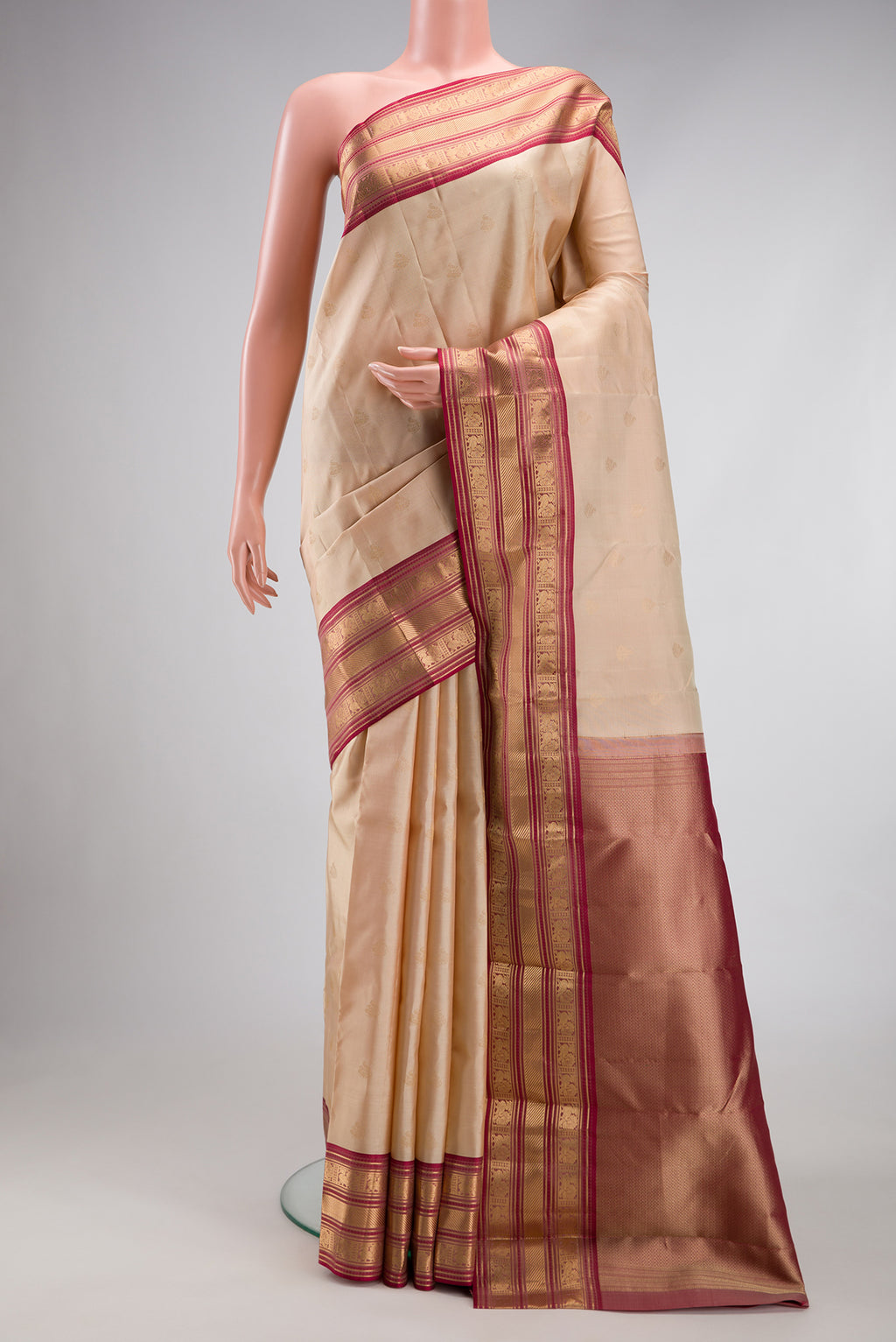 Beige Kanchipuram Silk Saree with Zari Butta on the body and Zari Border.  displayed on a mannequin