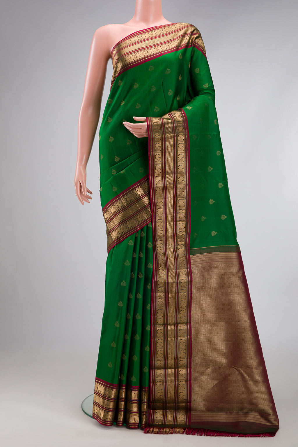 Green Kanchipuram Silk Saree with Zari Butta on the body and Zari Border.  displayed on a mannequin
