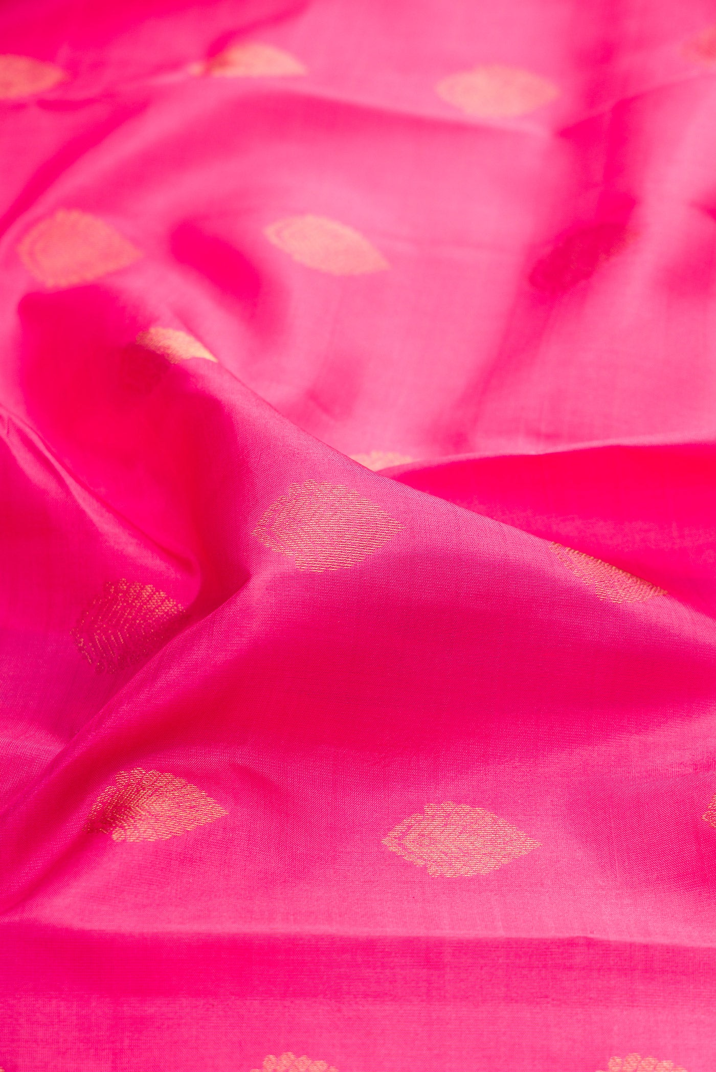 Close up of Pink Kanchipuram Silk Saree with Zari Butta on the body and Zari Border.  displaying folds