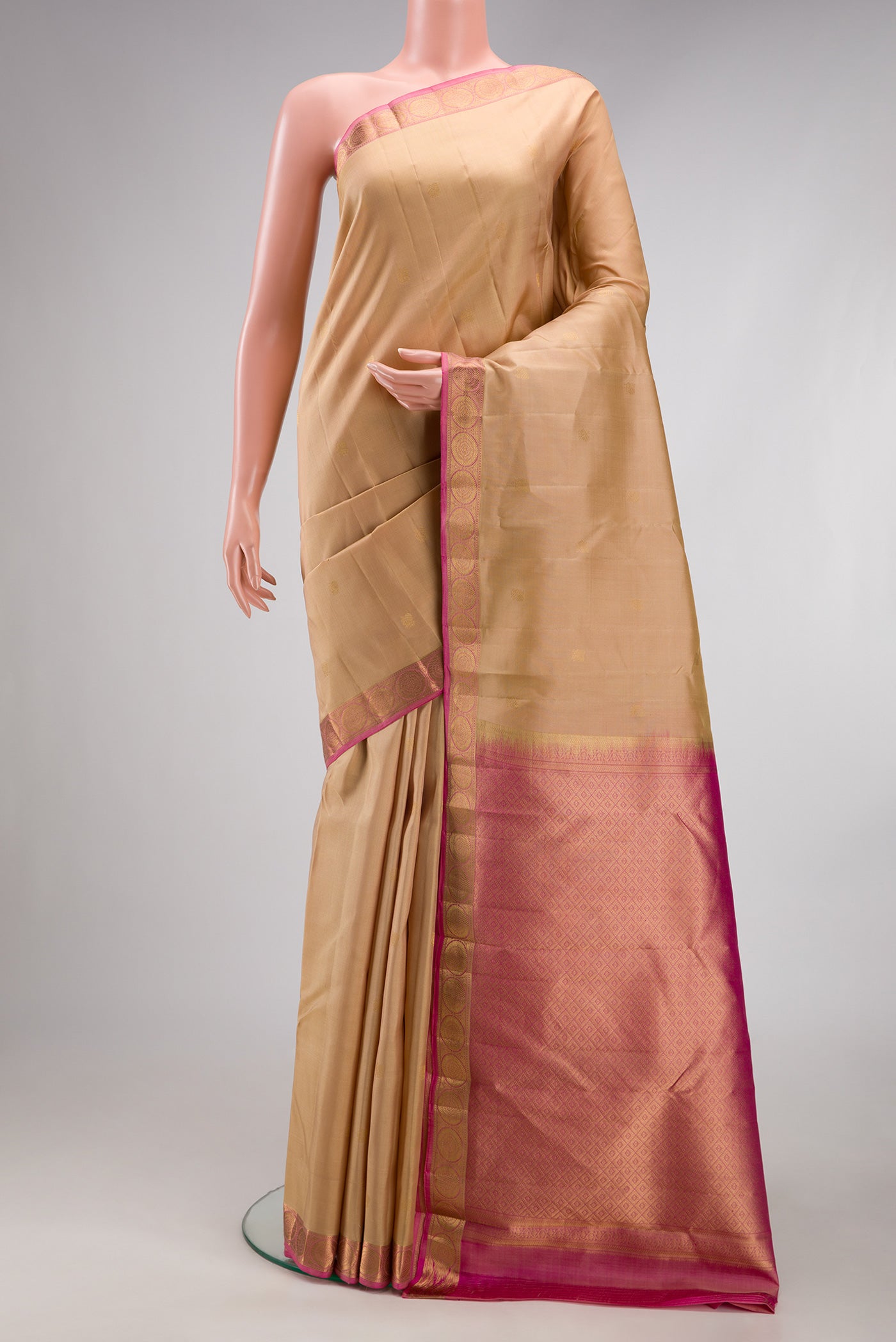 Beige Kanchipuram Silk Saree with Zari Butta on the body and Zari Border.  displayed on a mannequin