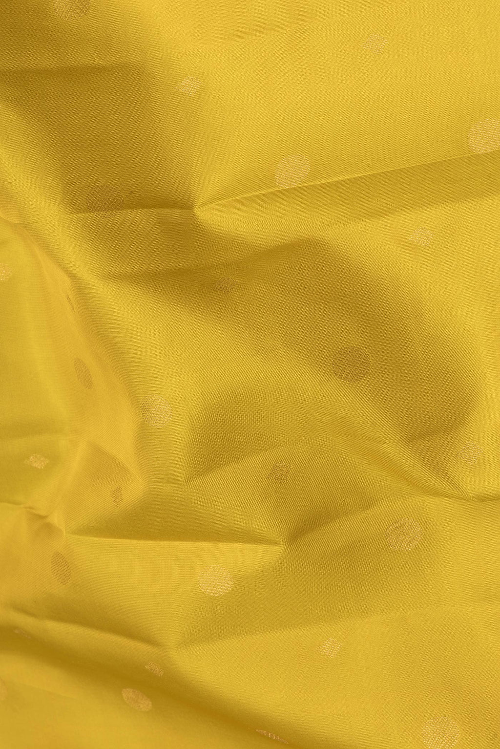 Close up of Lemon Yellow Kanchipuram Silk Saree with Zari Butta on the body and Zari Border.  displaying folds