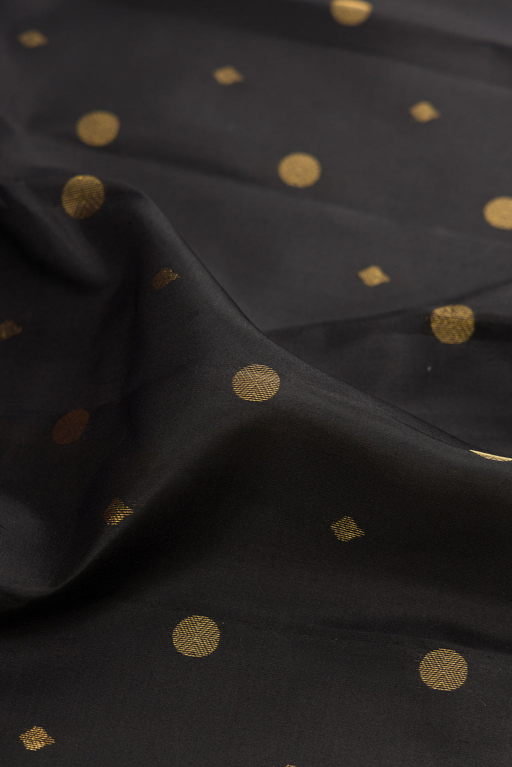 Close up of Black Kanchipuram Silk Saree with Zari Butta on the body and Zari Border.  displaying folds