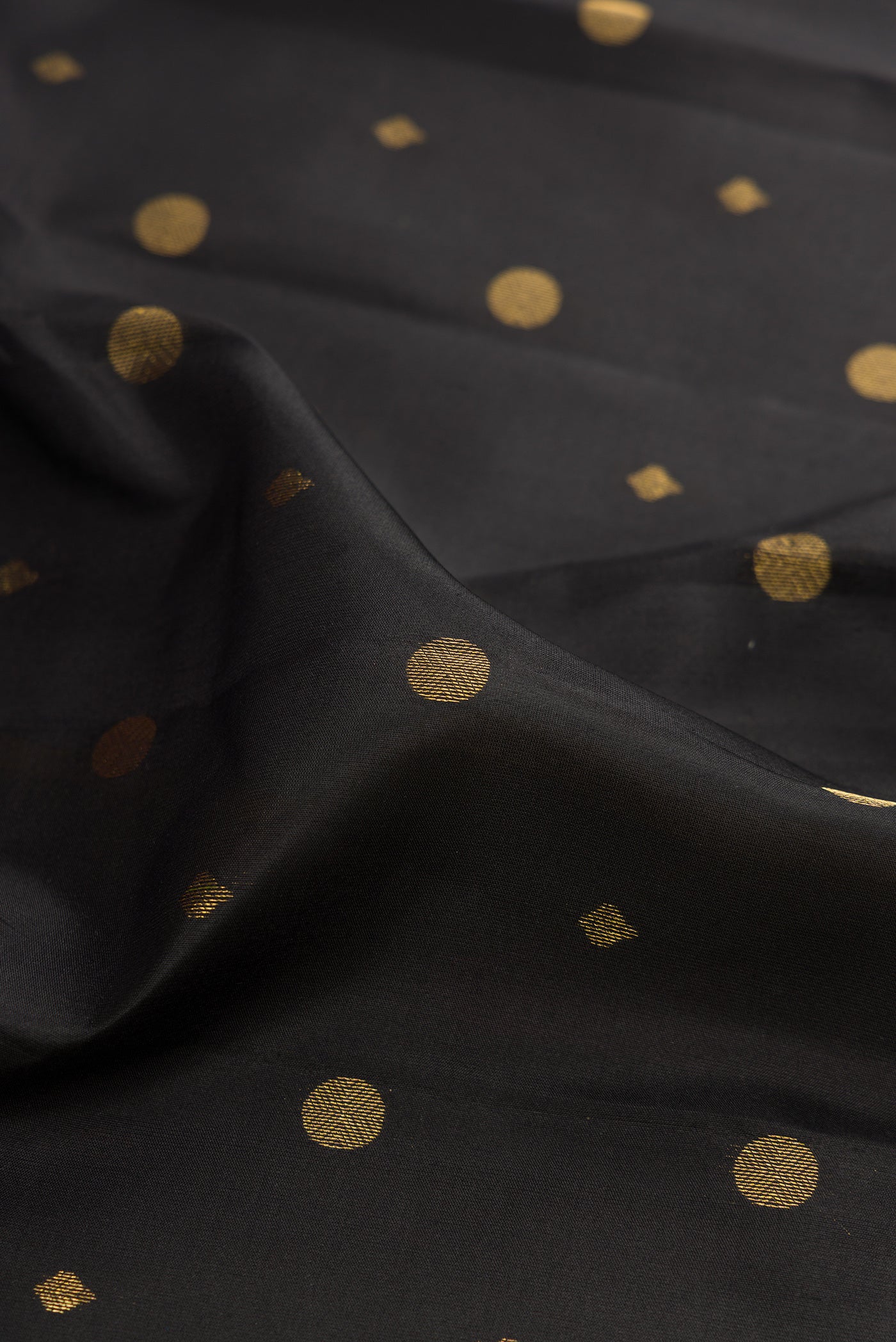 Close up of Black Kanchipuram Silk Saree with Zari Butta on the body and Zari Border.  displaying folds