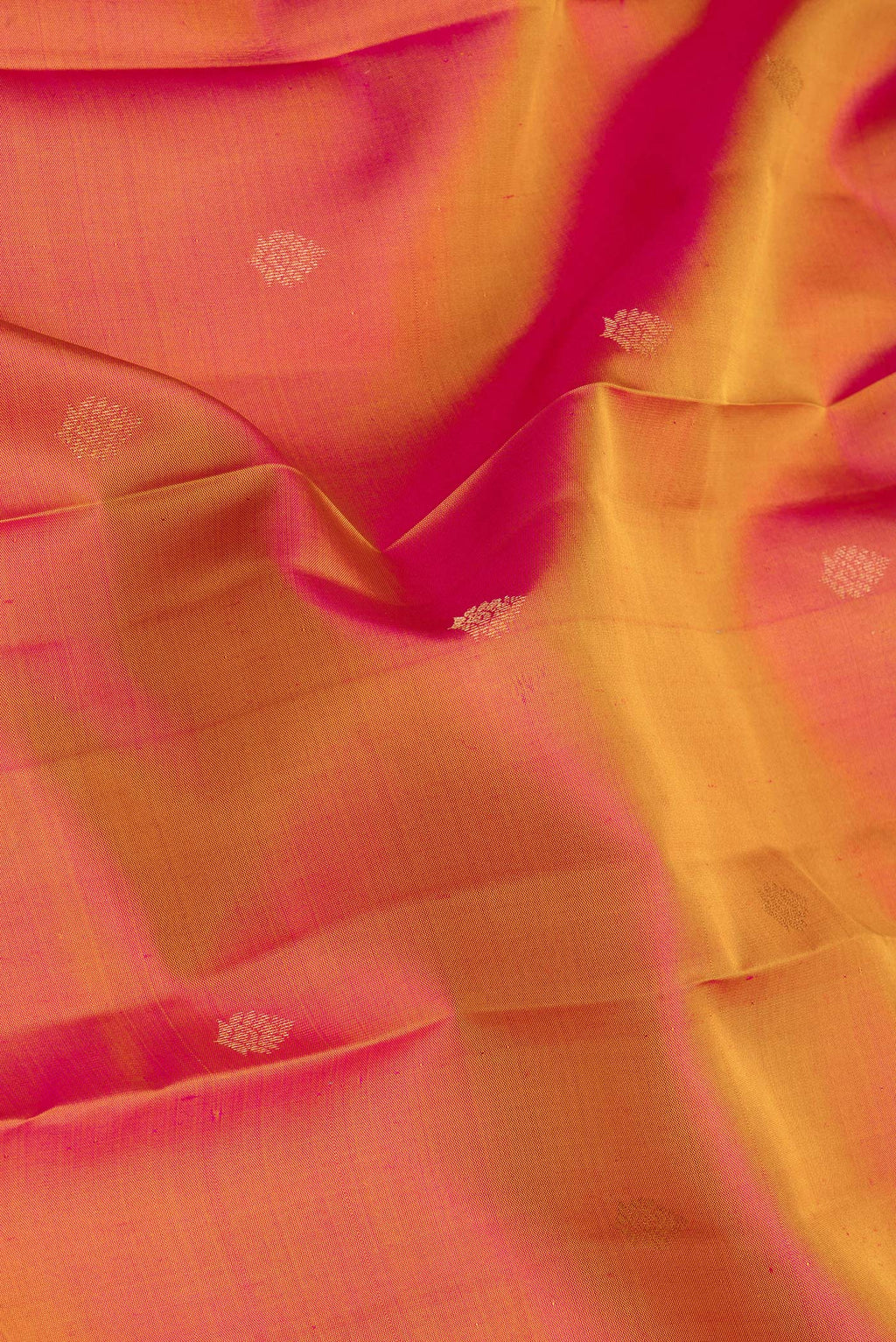 Close up of Pinkish Yellow Dual Tone Kanchipuram Silk Saree with Zari Butta on the body and Ganga Jamuna Border.  displaying folds