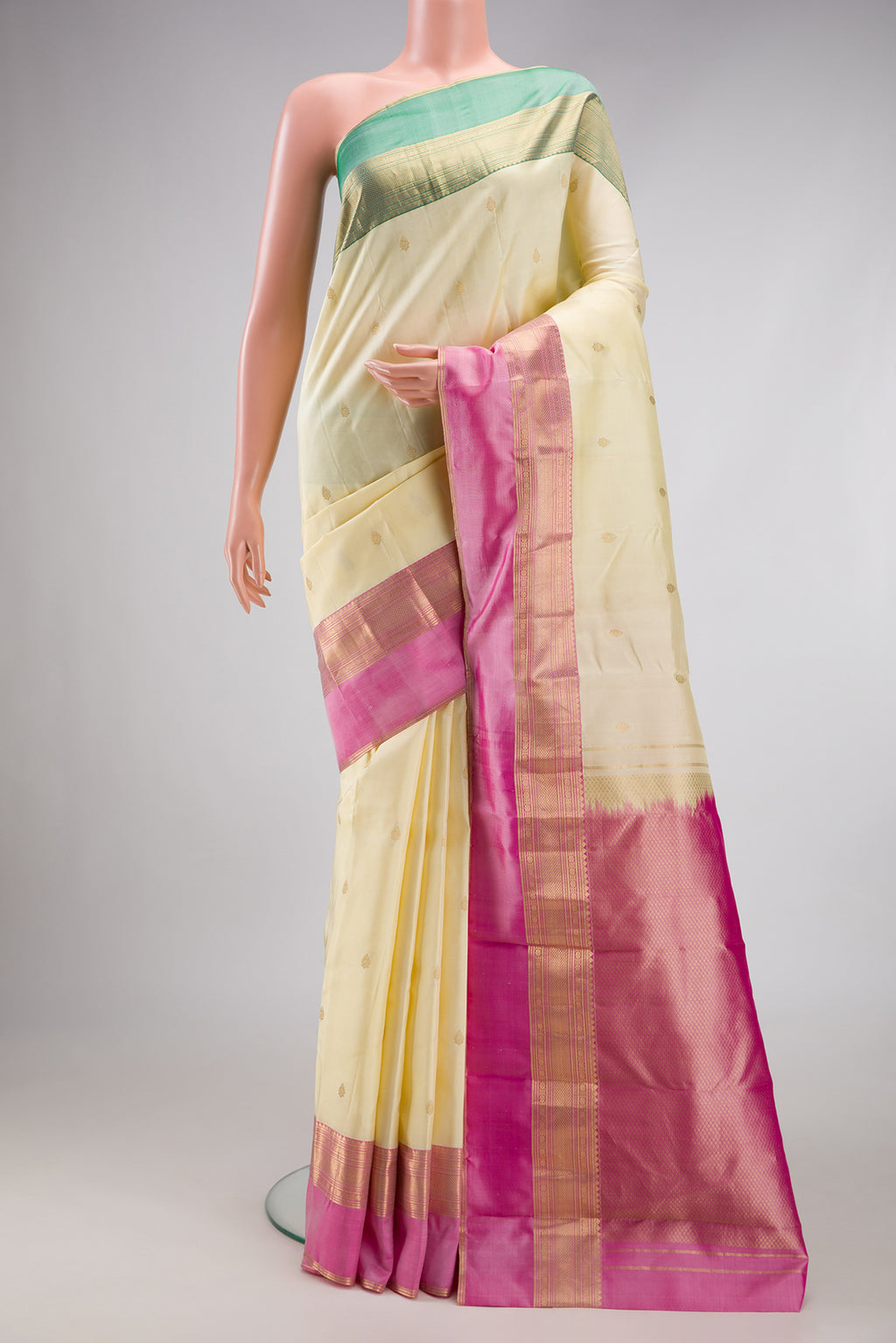 Cream Kanchipuram Silk Saree with Zari Butta on the body and Ganga Jamuna Border.  displayed on a mannequin