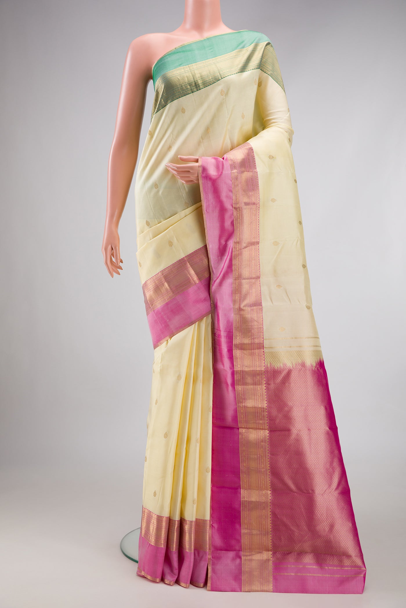 Cream Kanchipuram Silk Saree with Zari Butta on the body and Ganga Jamuna Border.  displayed on a mannequin