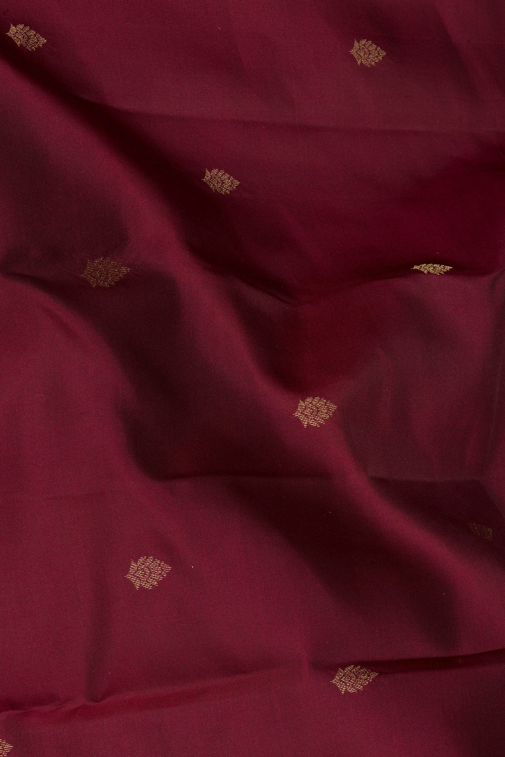 Close up of Maroon Kanchipuram Silk Saree with Zari Butta on the body and Ganga Jamuna Border.  displaying folds