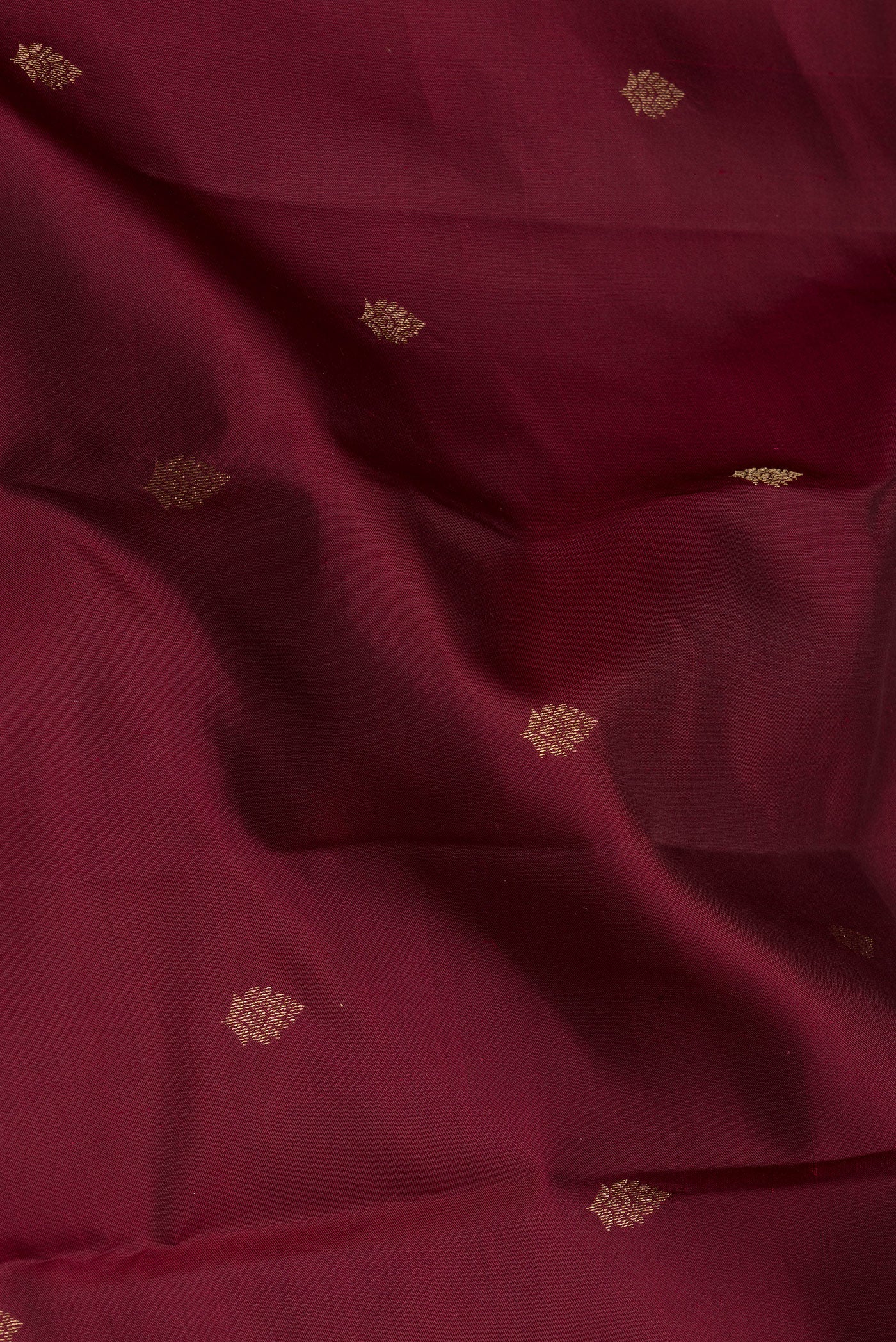 Close up of Maroon Kanchipuram Silk Saree with Zari Butta on the body and Ganga Jamuna Border.  displaying folds