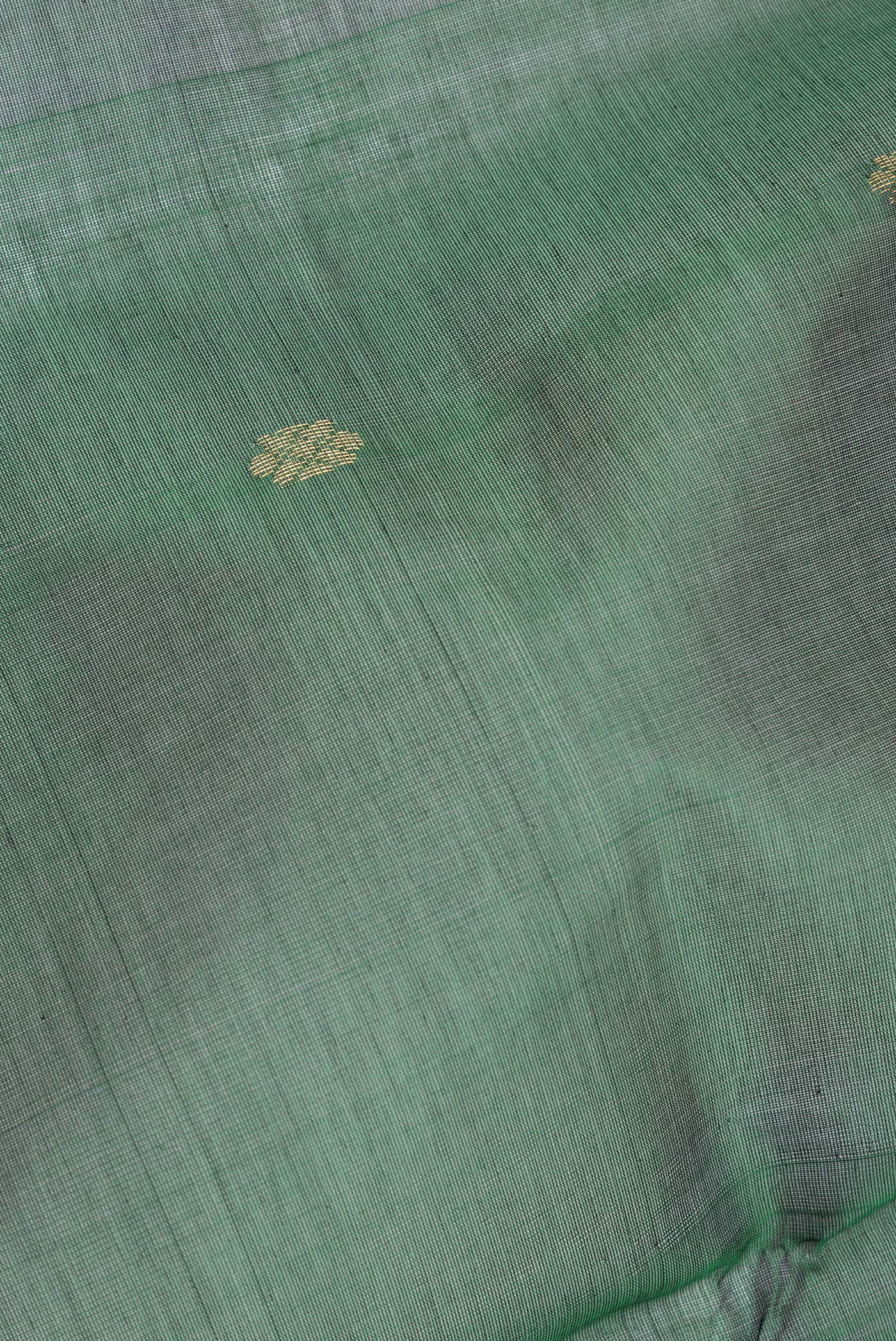 Close up of Bottle Green Silk Cotton Saree with Zari Butta on the body and Zari Border.  displaying folds