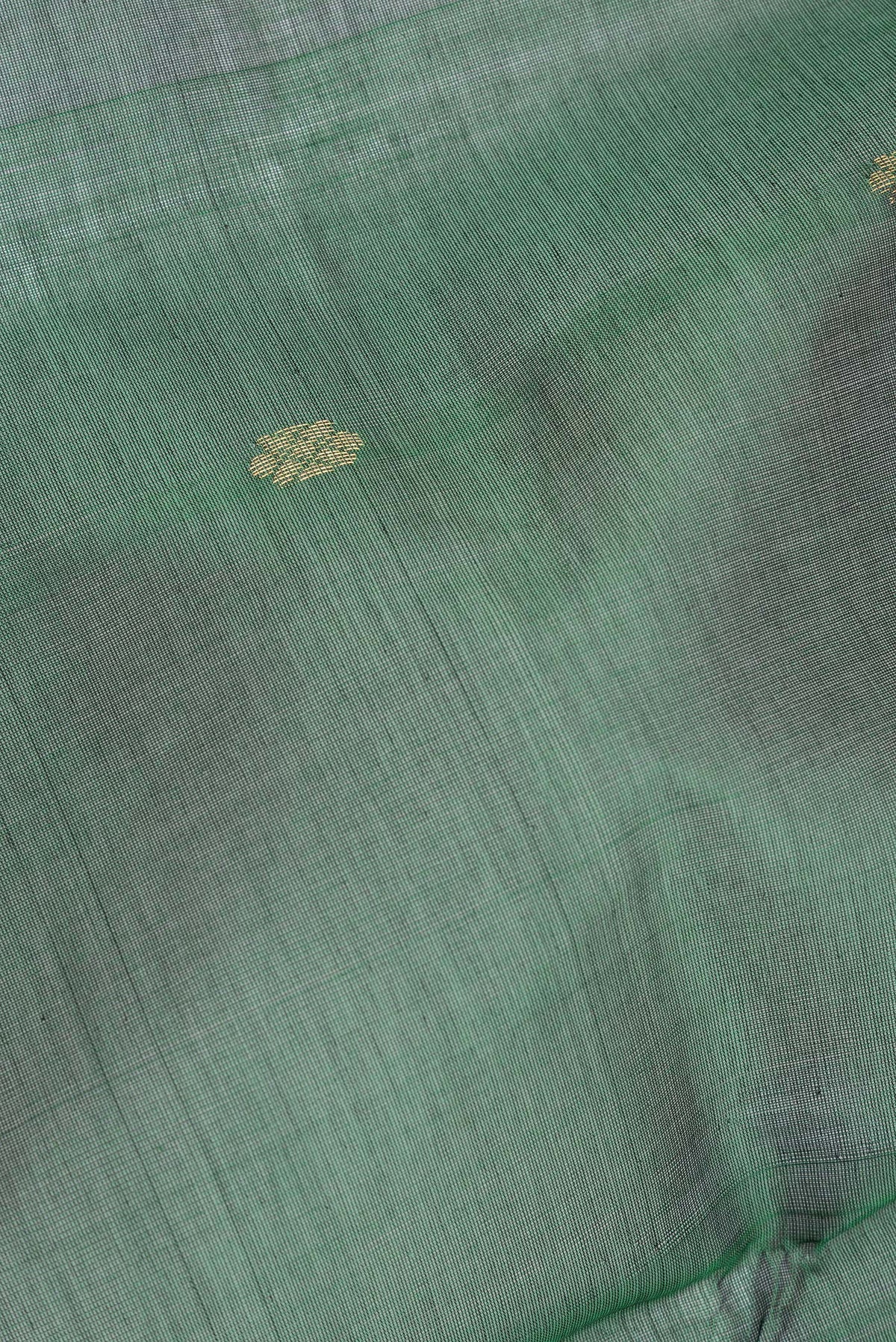 Close up of Bottle Green Silk Cotton Saree with Zari Butta on the body and Zari Border.  displaying folds