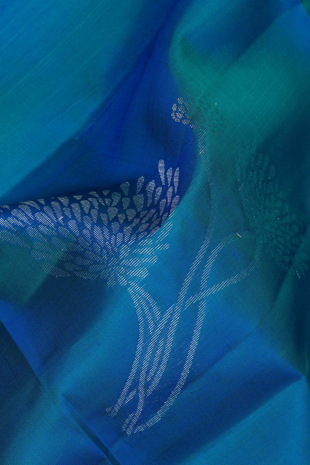 Close up of Pure Silk Peacock Blue Soft Saree with Zari Butta on the body and Zari Border.  displaying folds