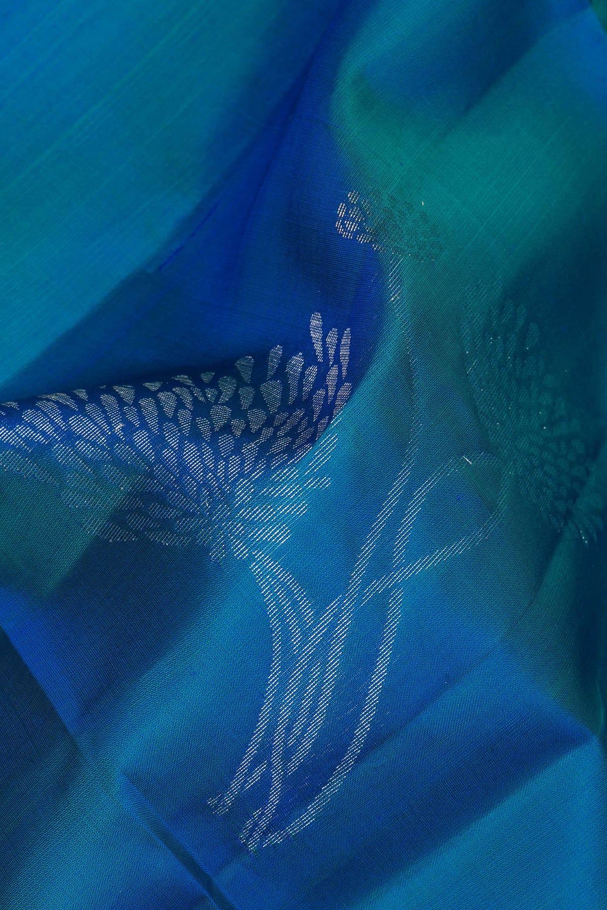 Close up of Pure Silk Peacock Blue Soft Saree with Zari Butta on the body and Zari Border.  displaying folds
