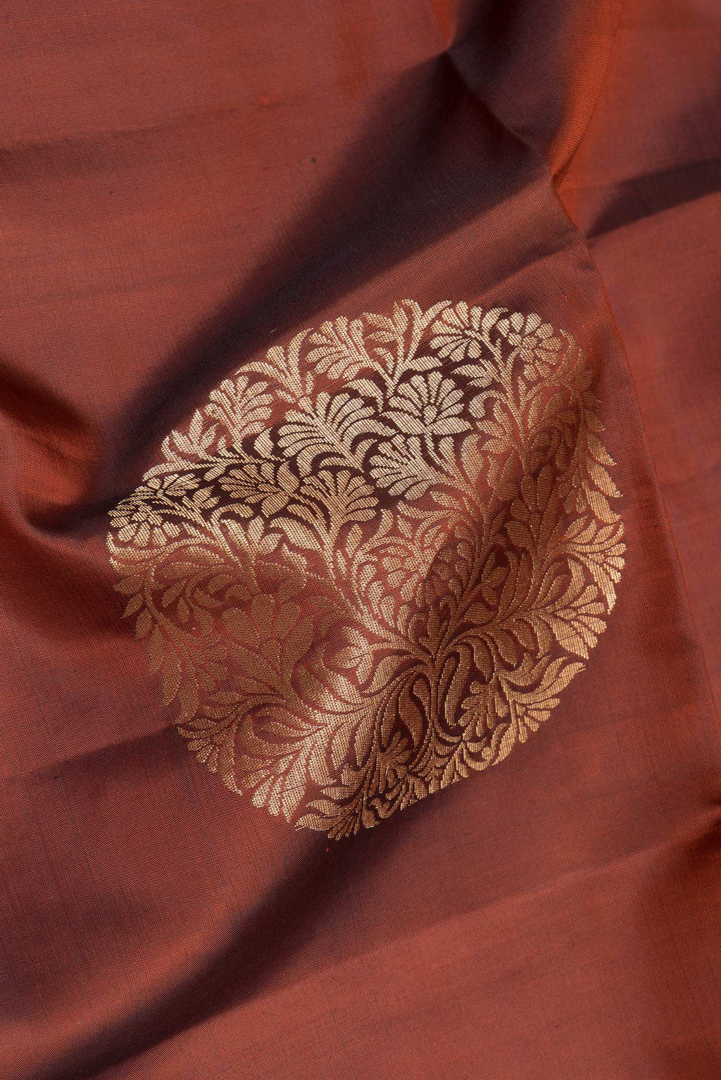 Close up of Rust Soft Silk Saree with Zari Butta on the body and Without Border.  displaying folds