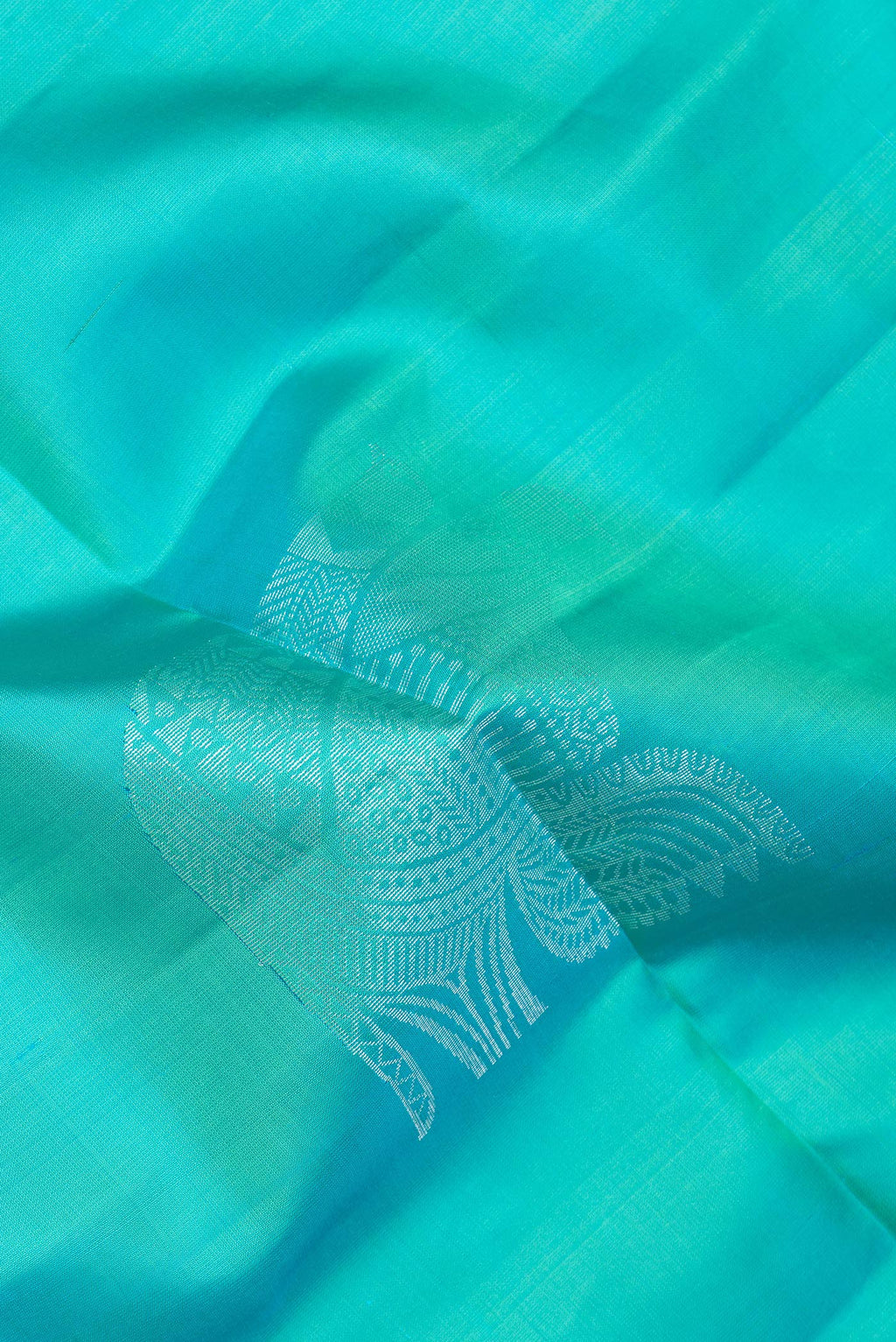 Close up of Pure Silk Turquoise Soft Saree with Zari Butta on the body and Zari Border.  displaying folds