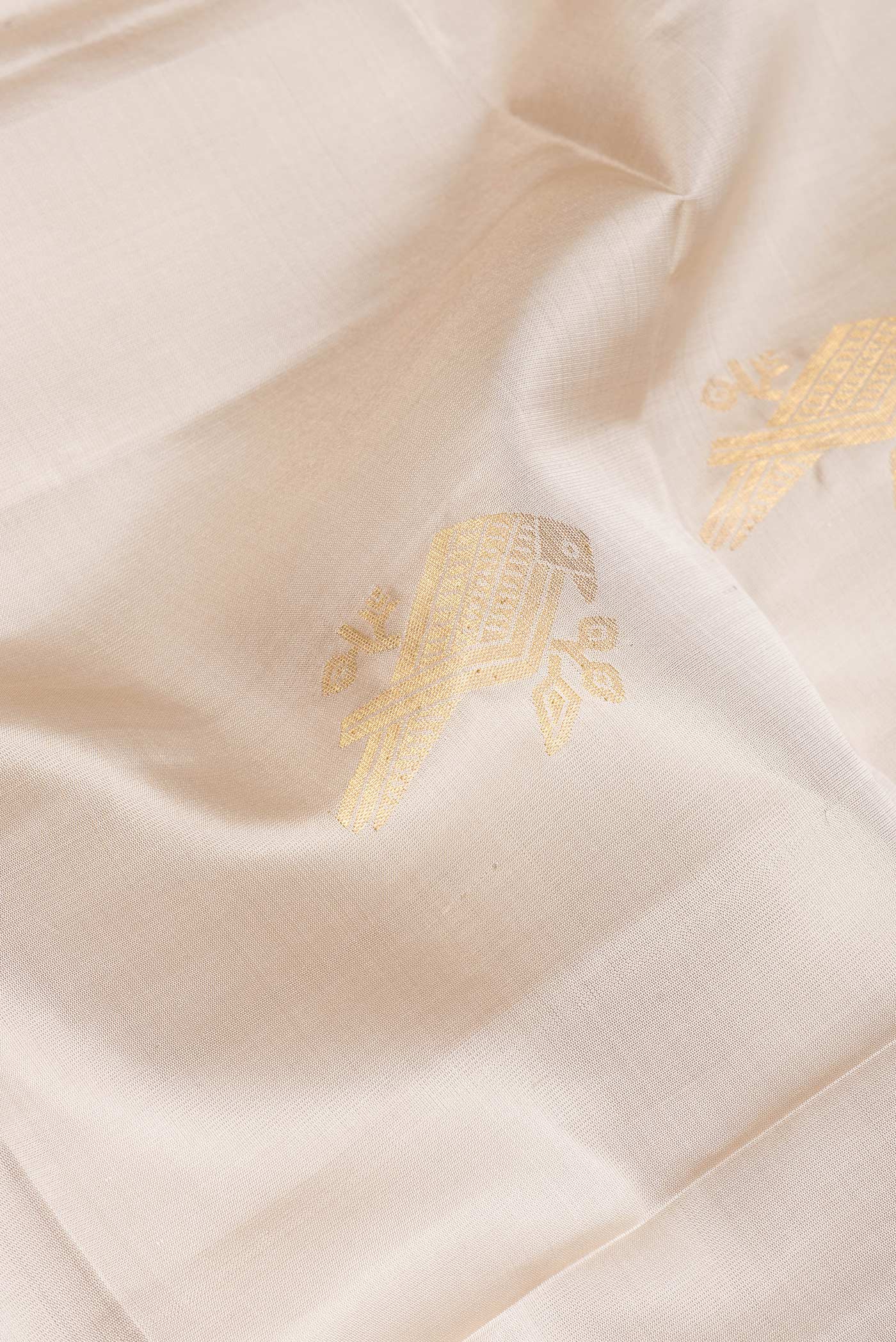 Close up of Beige Soft Silk Saree with Zari Butta on the body and Zari Border.  displaying folds