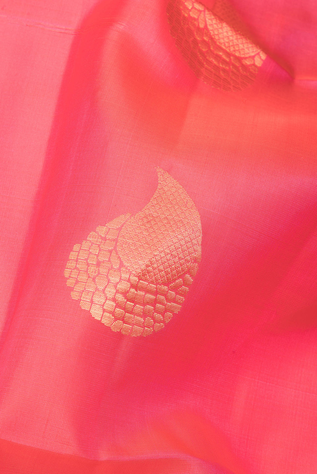 Close up of Pure Silk Coral Soft Saree with Zari Butta on the body and Zari Border.  displaying folds