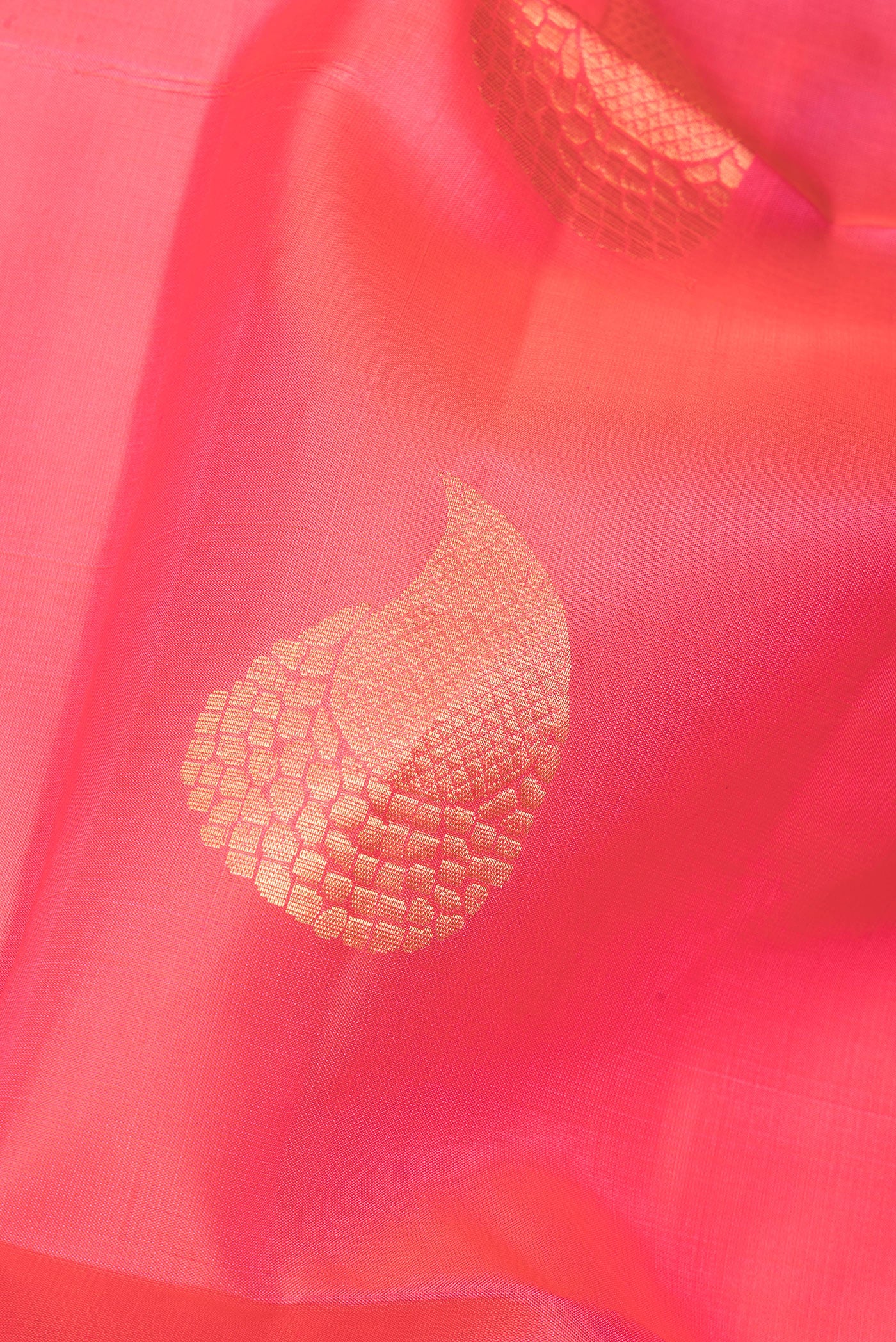 Close up of Pure Silk Coral Soft Saree with Zari Butta on the body and Zari Border.  displaying folds