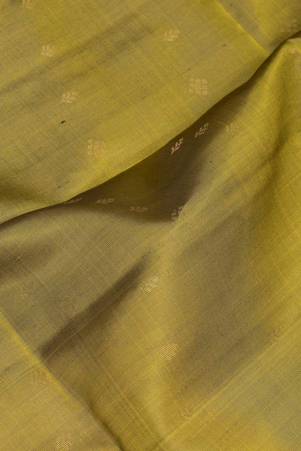 Close up of Mehandi Green Soft Silk Saree with Zari Butta on the body and Zari Border.  displaying folds