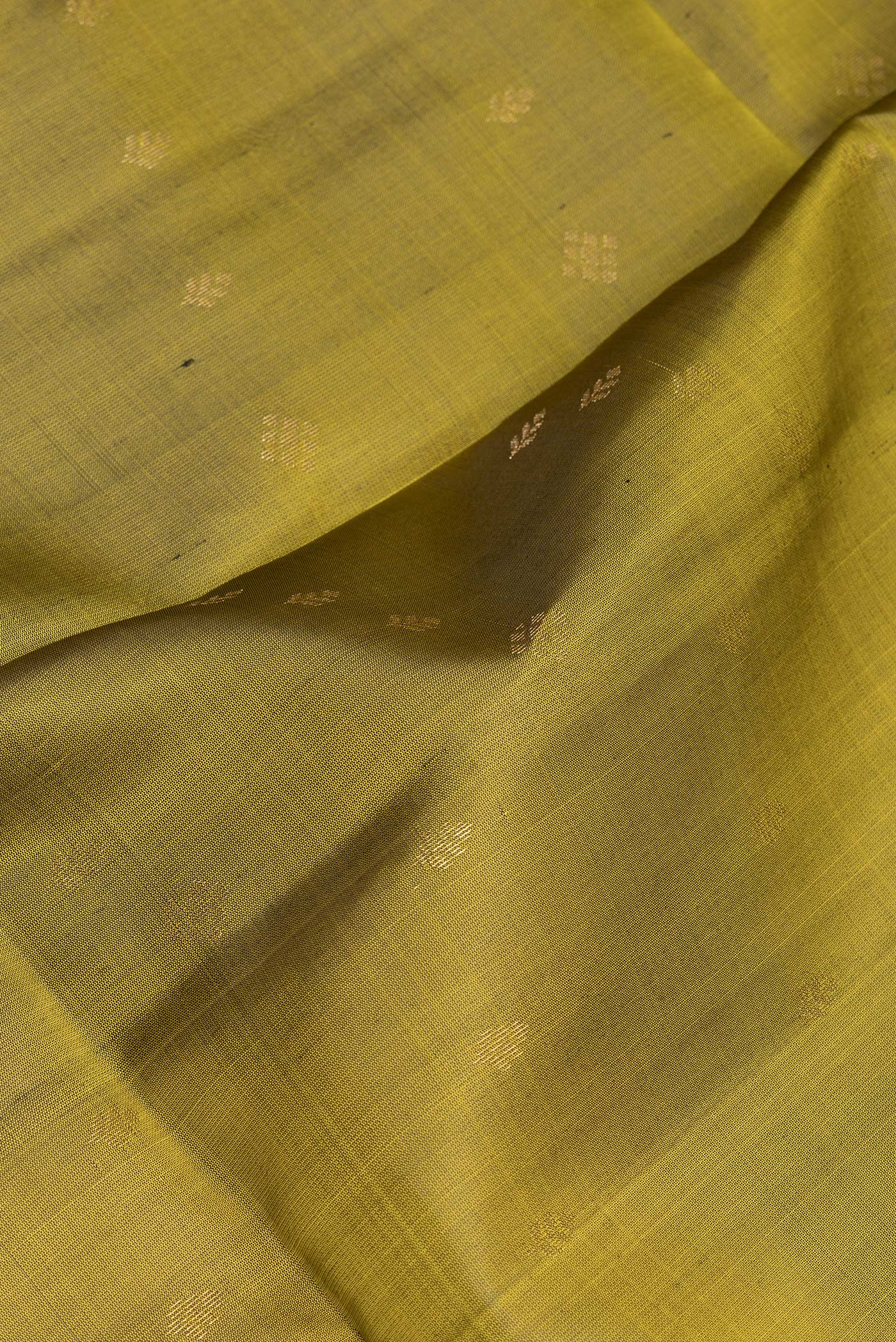 Close up of Mehandi Green Soft Silk Saree with Zari Butta on the body and Zari Border.  displaying folds