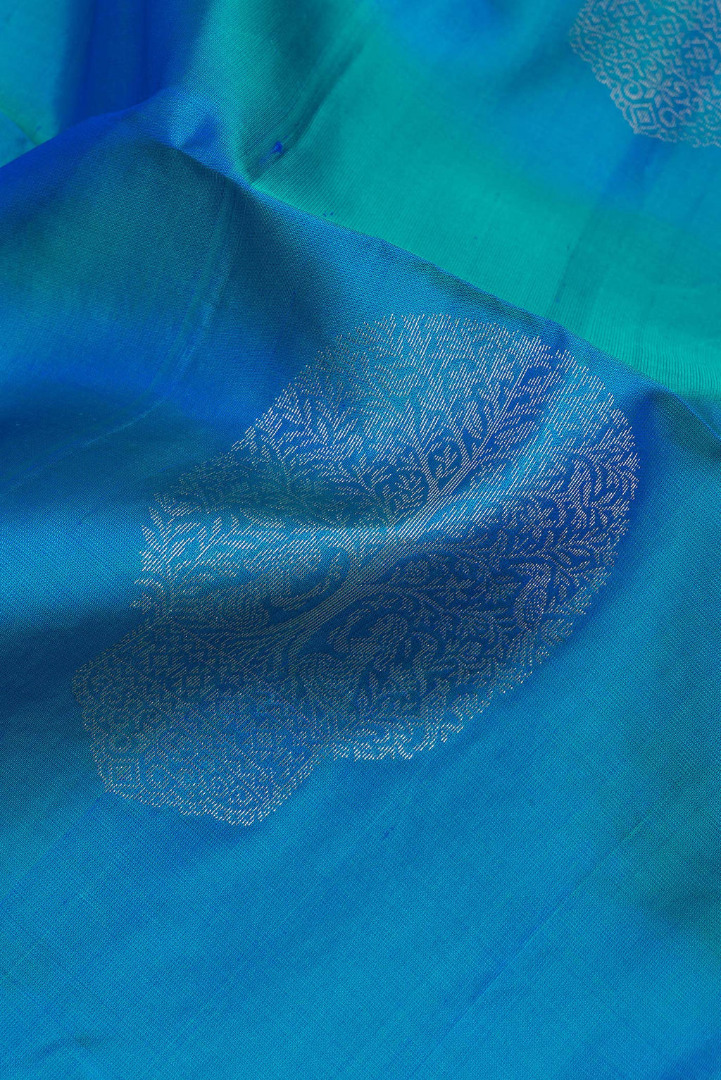 Close up of Pure Silk Peacock Blue Soft Saree with Zari Butta on the body and Zari Border.  displaying folds