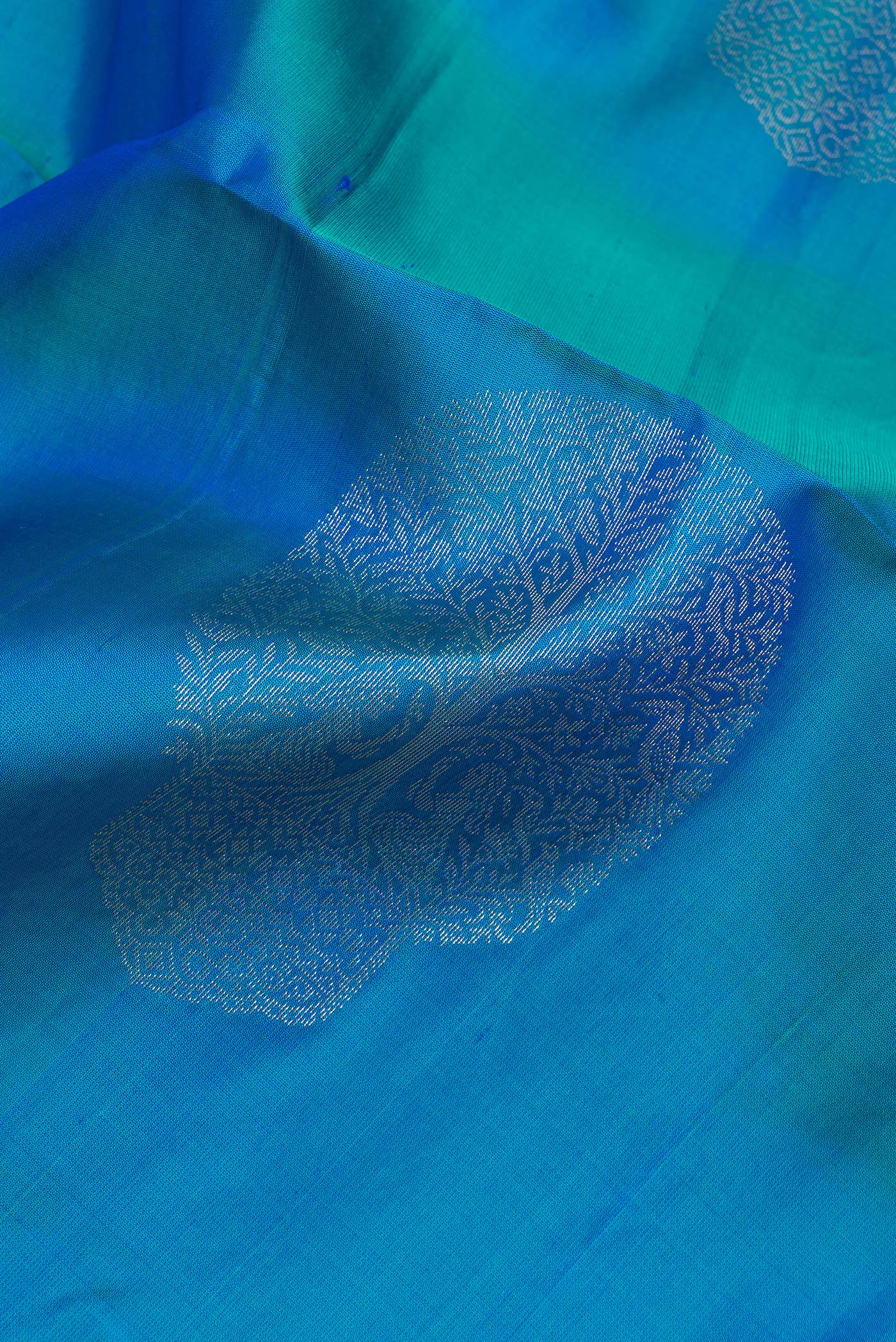Close up of Pure Silk Peacock Blue Soft Saree with Zari Butta on the body and Zari Border.  displaying folds