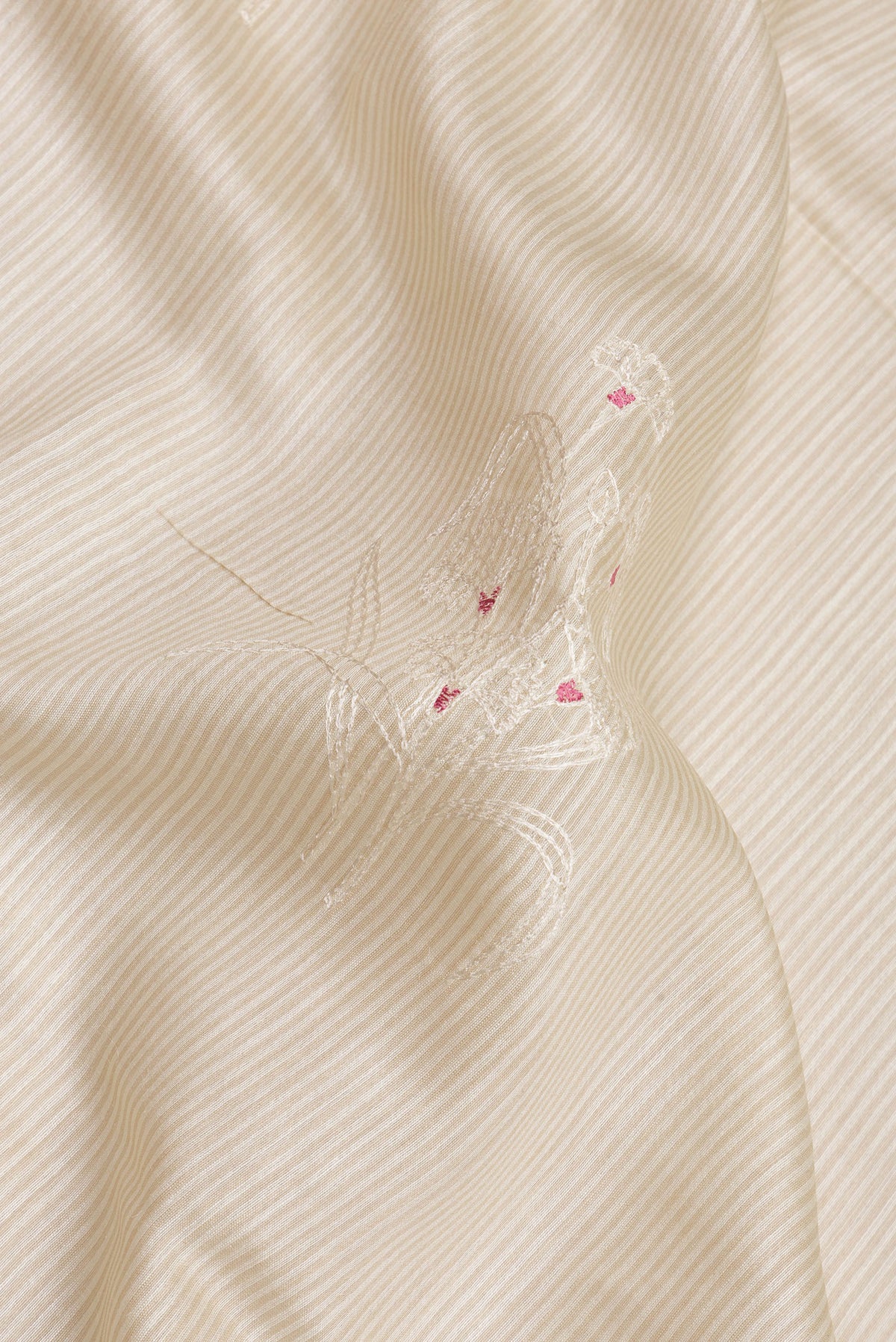Close up of Beige Tussar Saree with Embroidery on the body and Embroidery Border.  displaying folds