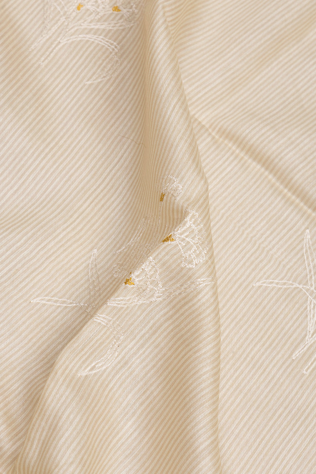Close up of Beige Tussar Saree with Embroidery on the body and Embroidery Border.  displaying folds