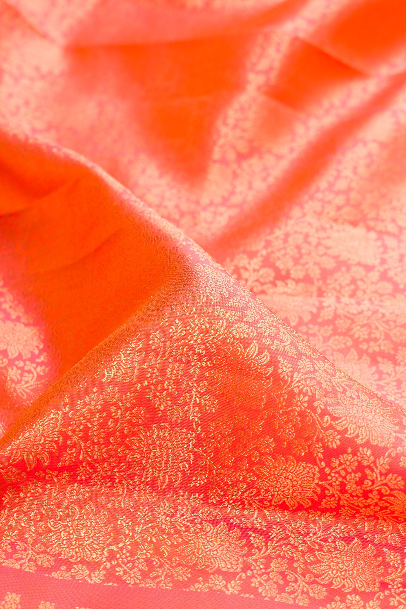 Close up of Coral Dual Tone Kanchipuram Silk Saree with Zari Brocade on the body and Zari Border.  displaying folds