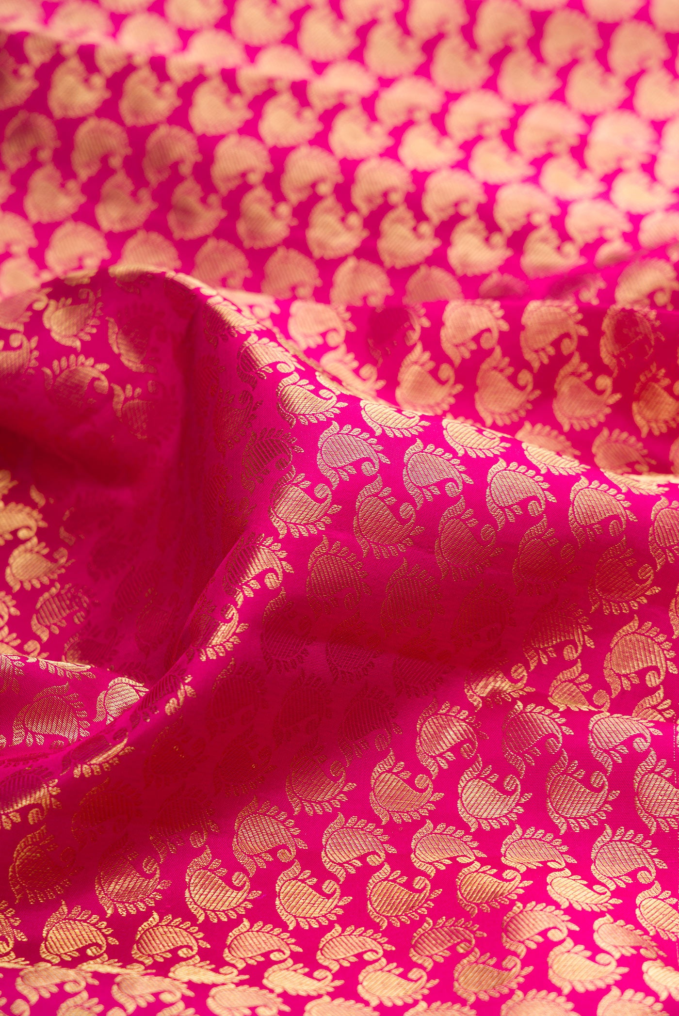 Close up of Rani Pink Kanchipuram Silk Saree with Zari Brocade on the body and Zari Border.  displaying folds