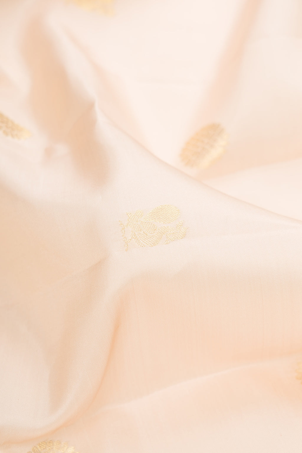 Close up of Cream Kanchipuram Silk Saree with Zari Butta on the body and Zari Border.  displaying folds