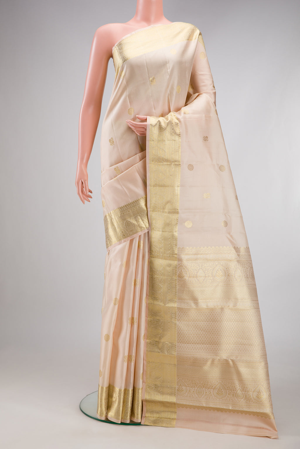 Cream Kanchipuram Silk Saree with Zari Butta on the body and Zari Border.  displayed on a mannequin