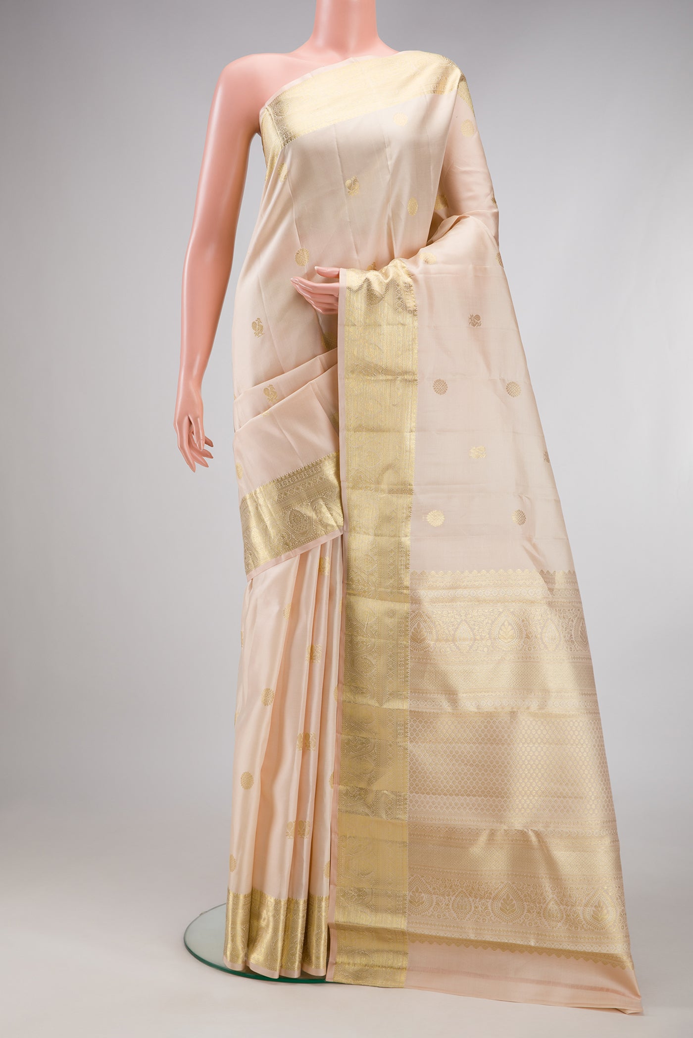 Cream Kanchipuram Silk Saree with Zari Butta on the body and Zari Border.  displayed on a mannequin