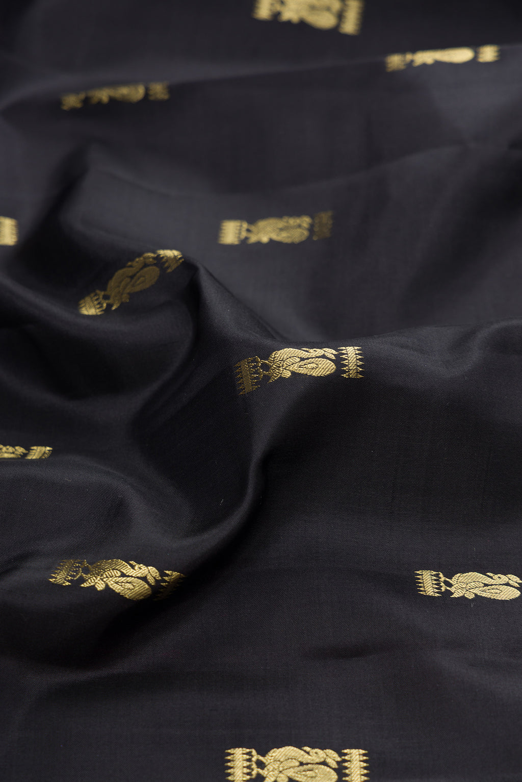 Close up of Black Kanchipuram Silk Saree with Zari Butta on the body and Zari Border.  displaying folds