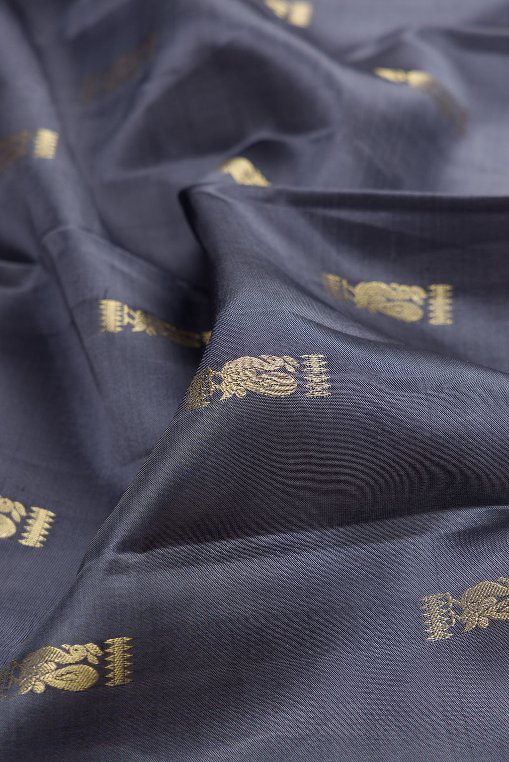 Close up of Pure Silk Grey Kanchipuram Saree with Zari Butta on the body and Zari Border.  displaying folds
